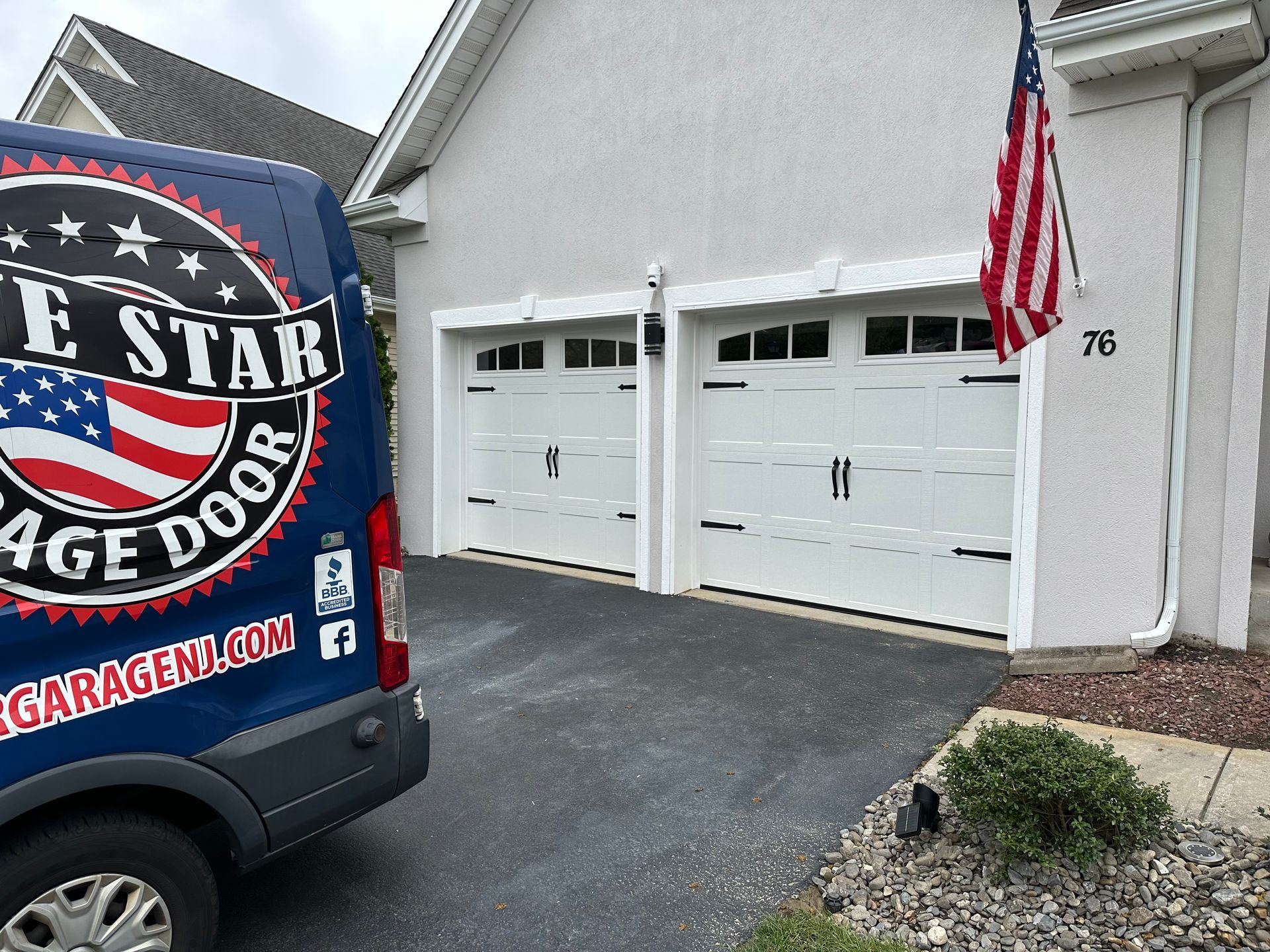 A blue e star garage door van is parked in front of a white house