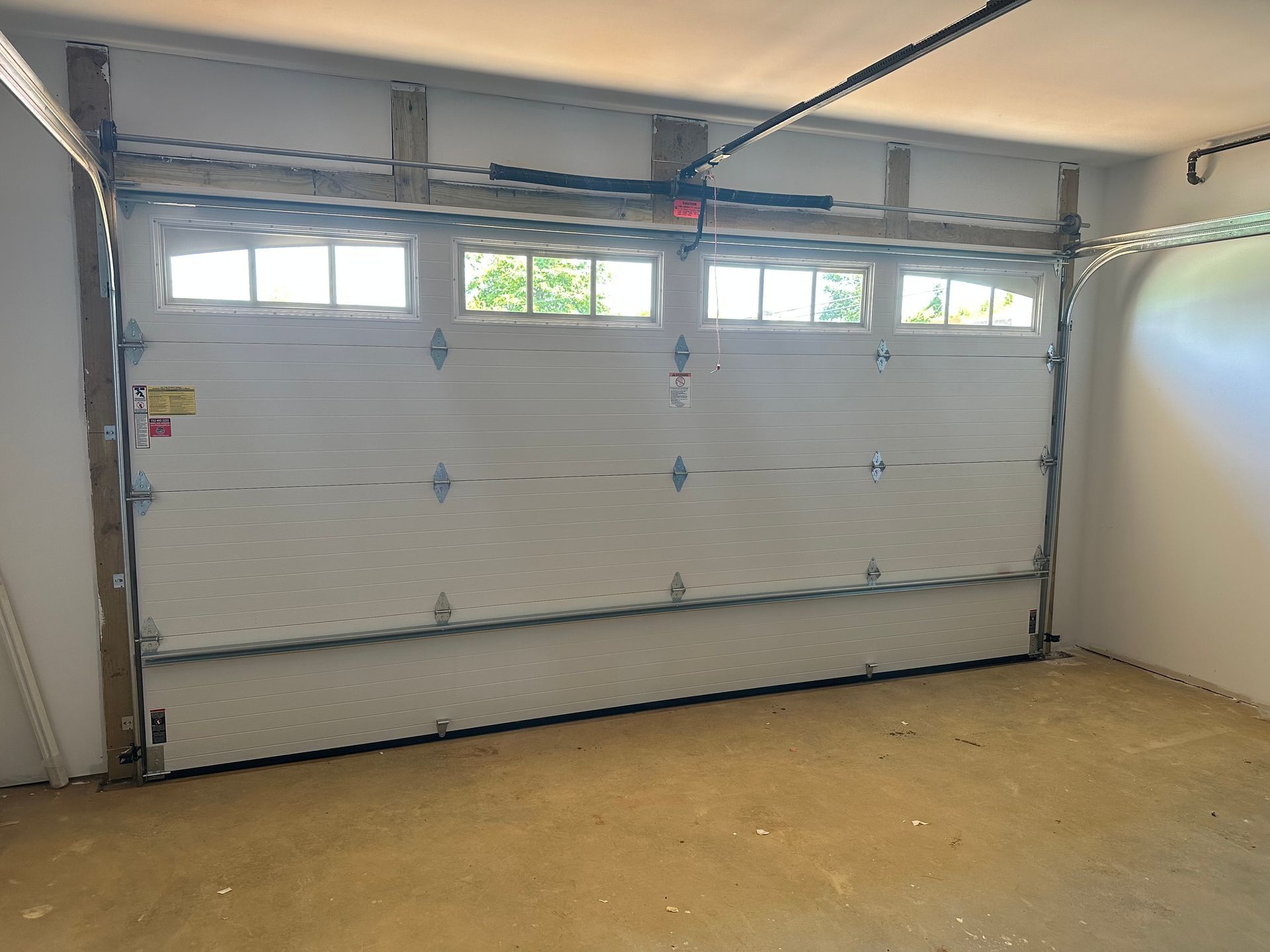An empty garage with a garage door open and a window.