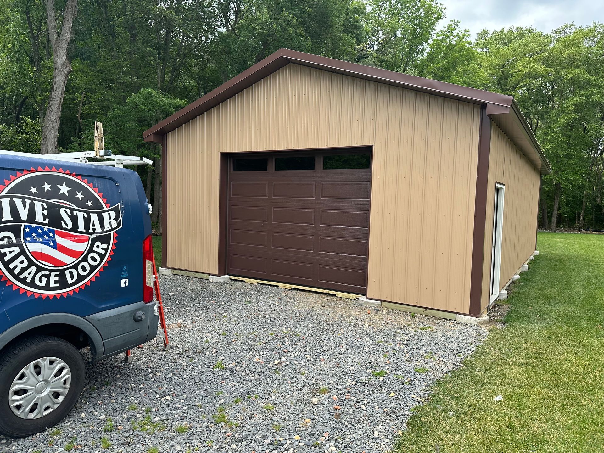 A blue van is parked in front of a garage.