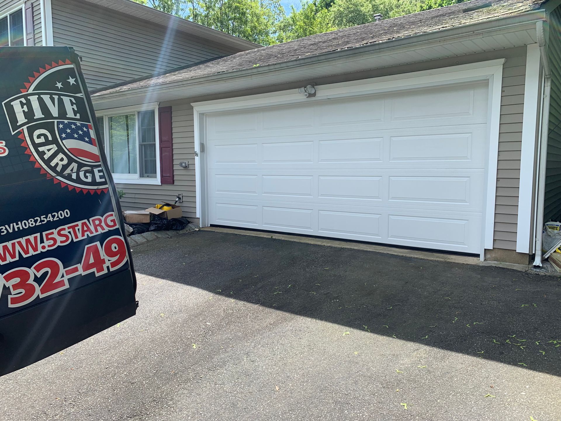 A white garage door is sitting in front of a house.