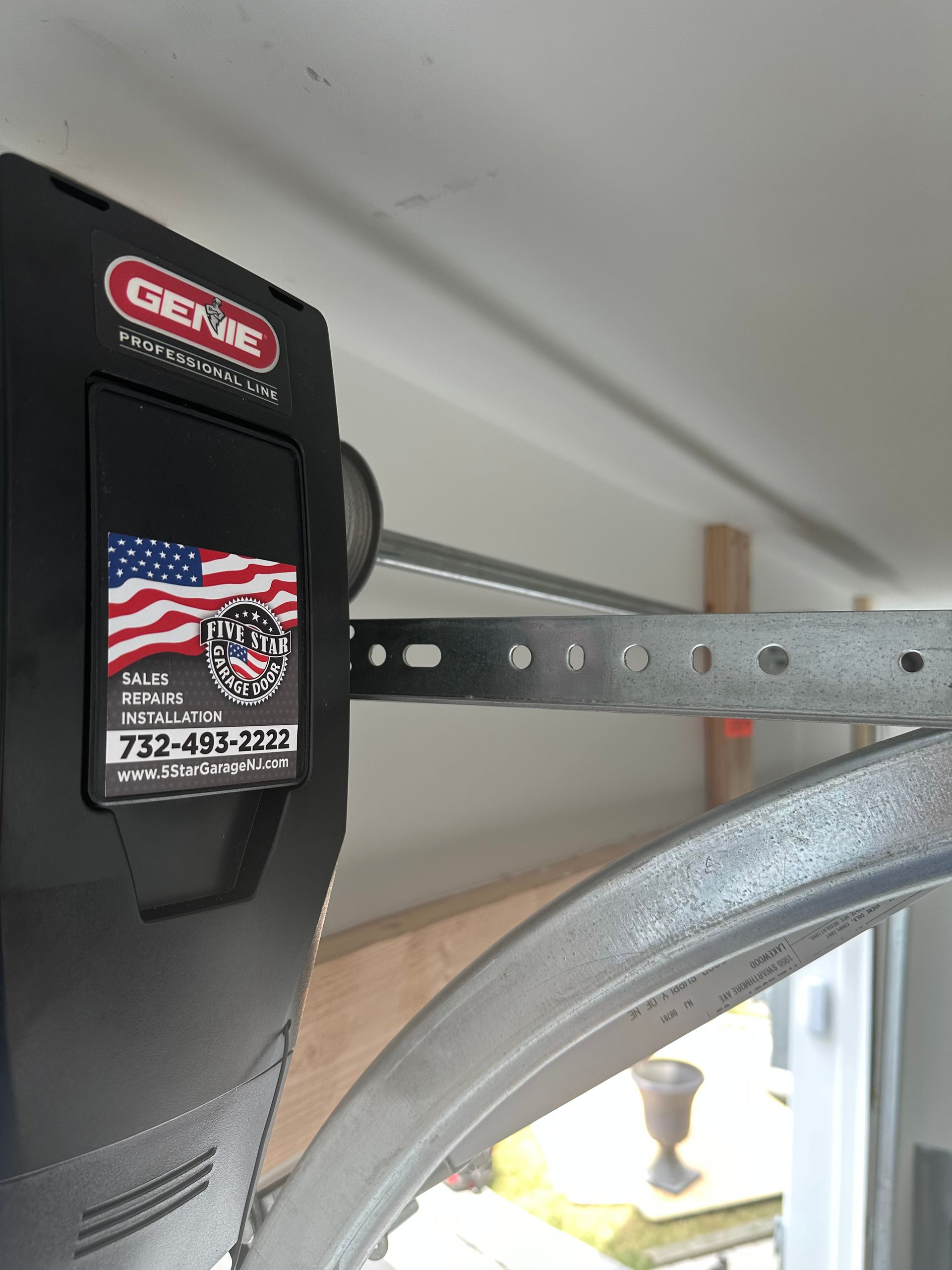 A garage door opener with an american flag on it is hanging from the ceiling.