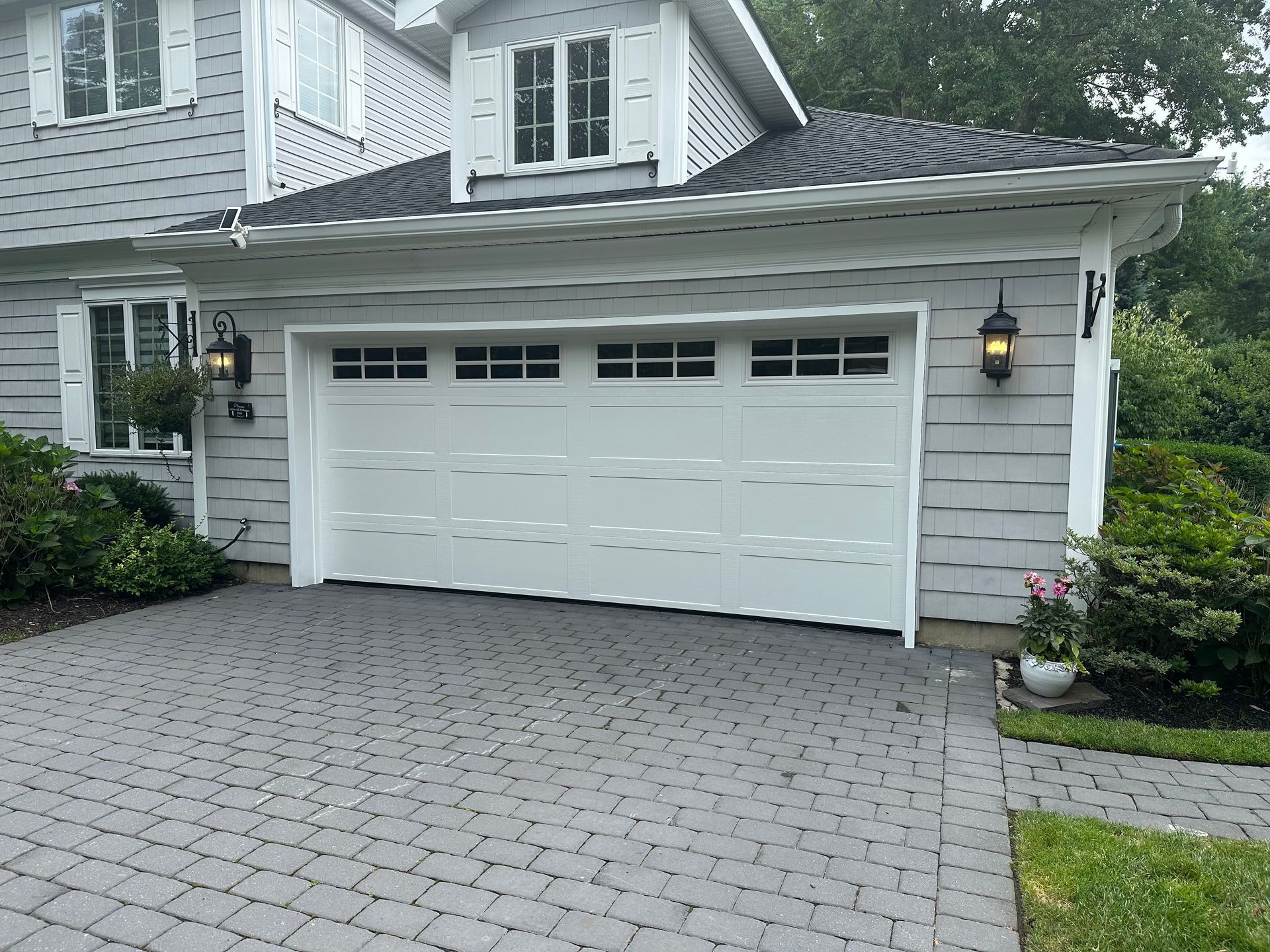 A white garage door is open in front of a white house.