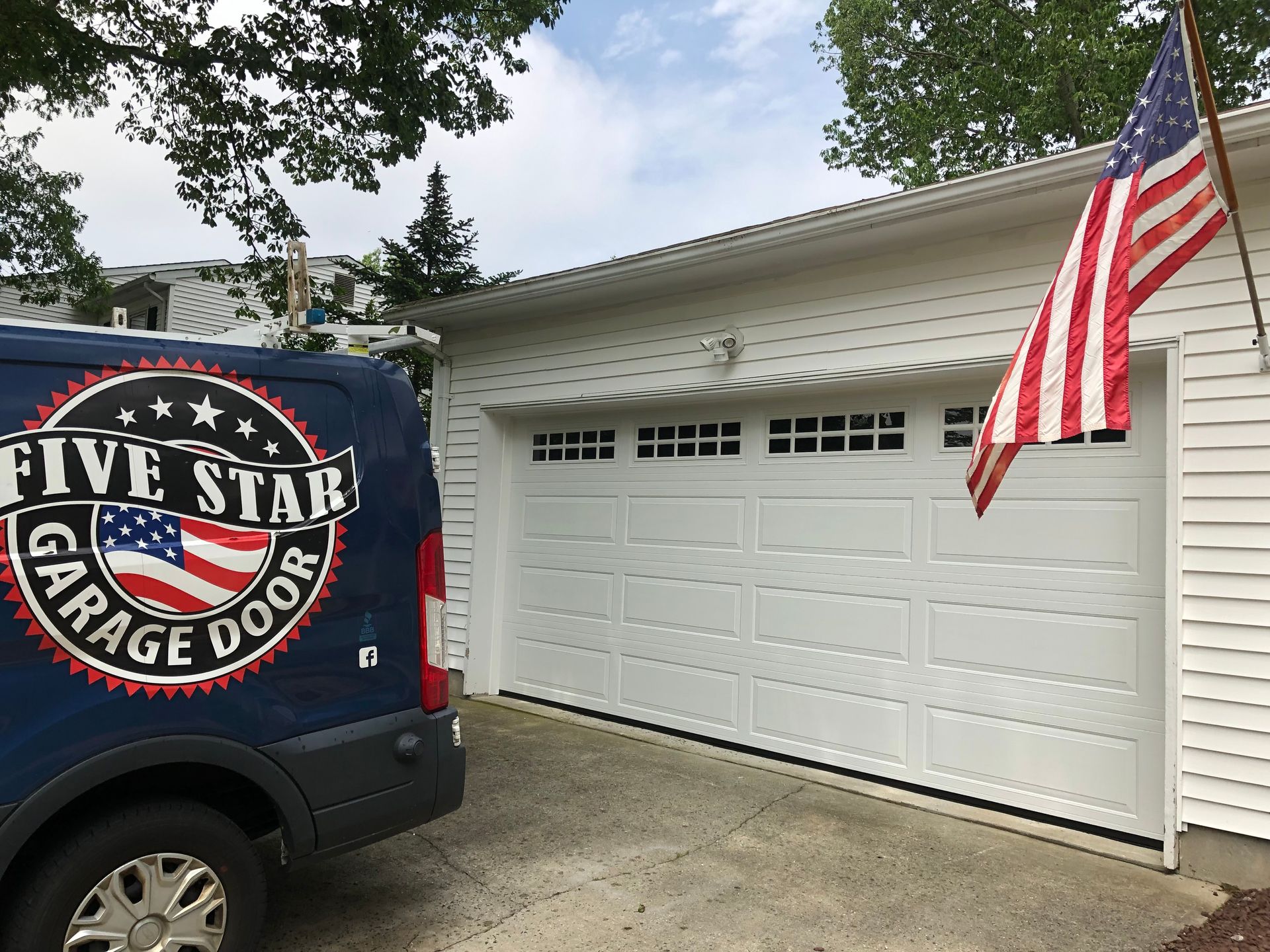 A five star garage door van is parked in front of a white garage door.