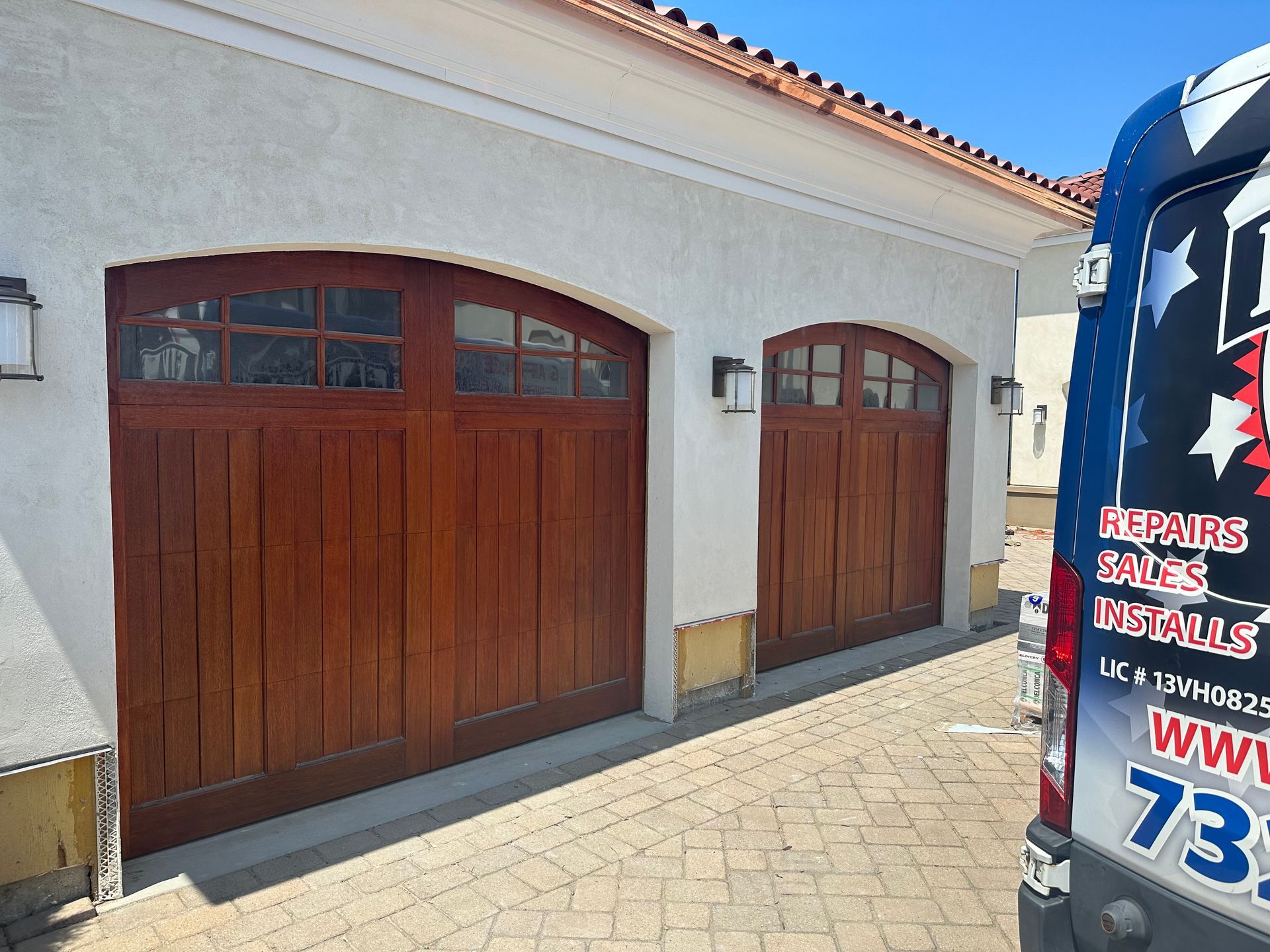 A van is parked in front of a house with wooden garage doors.