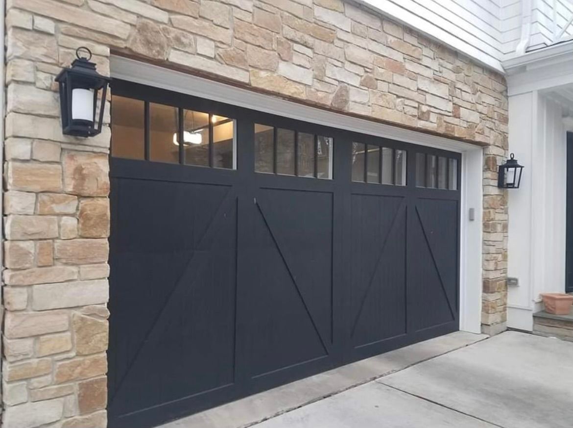 A black garage door is on the side of a brick building.