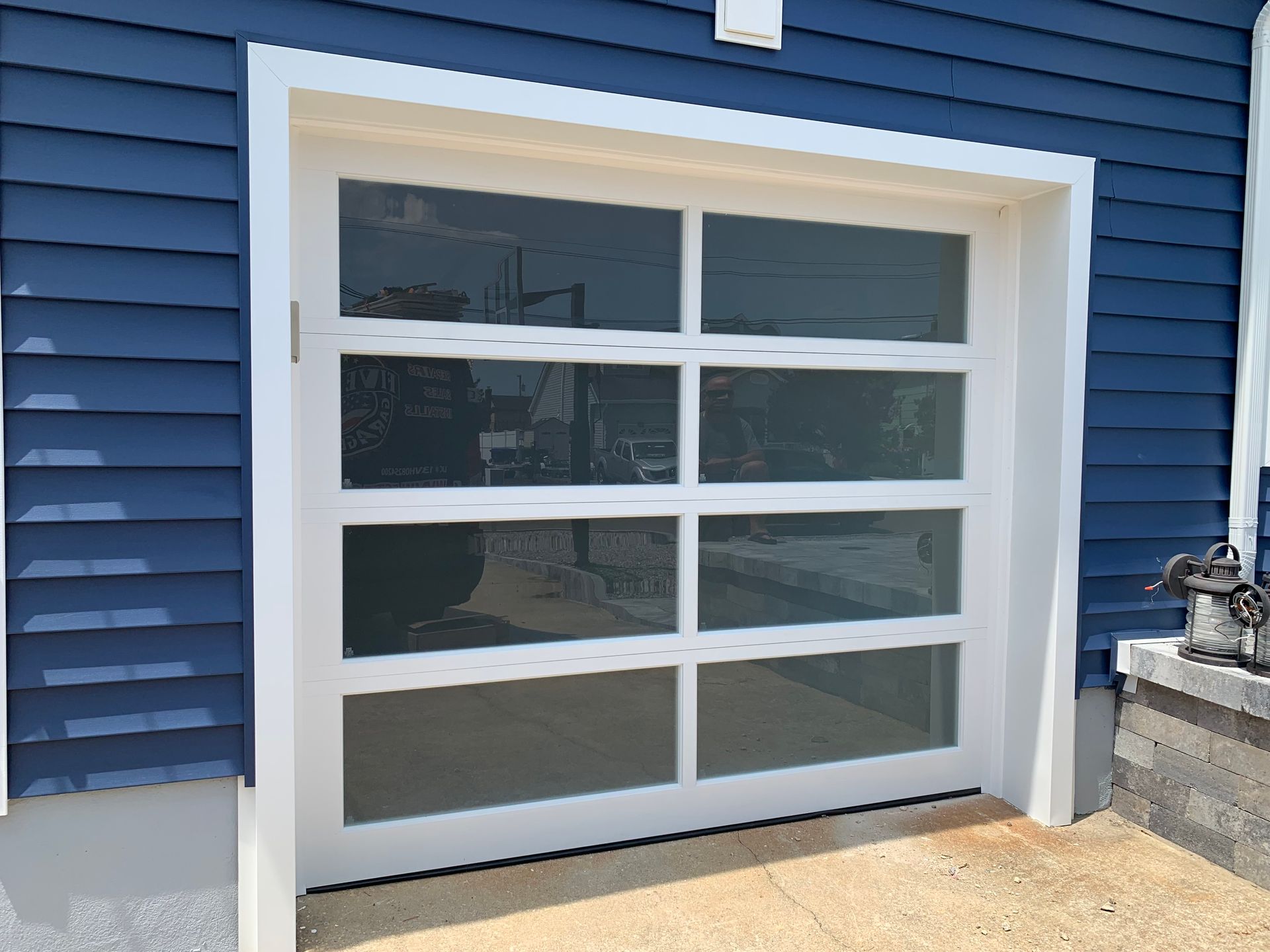 A white garage door is on the side of a blue house.