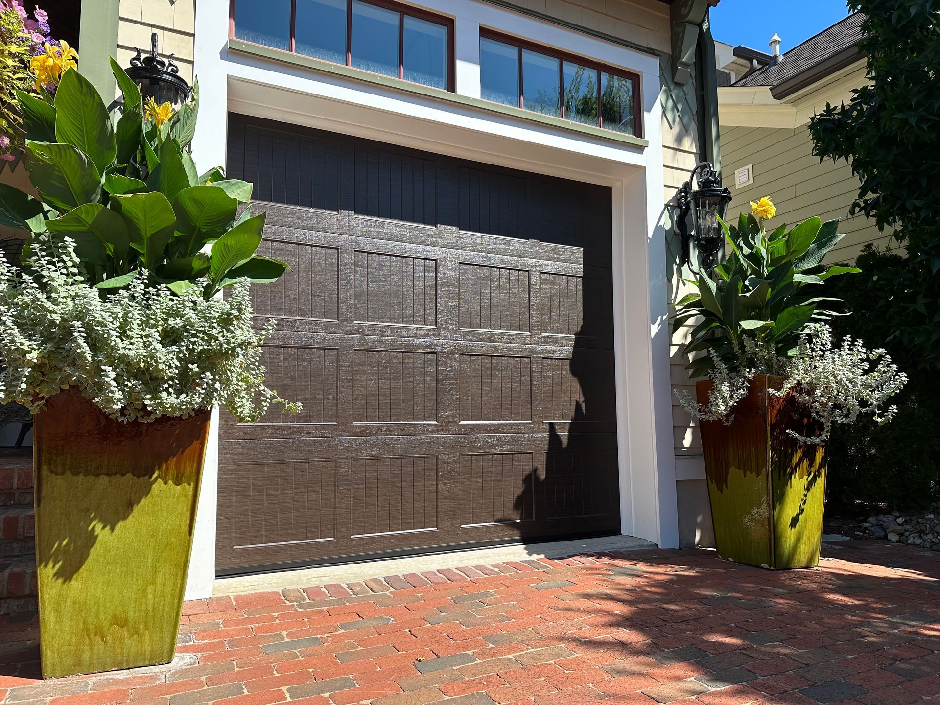 Two potted plants are in front of a garage door