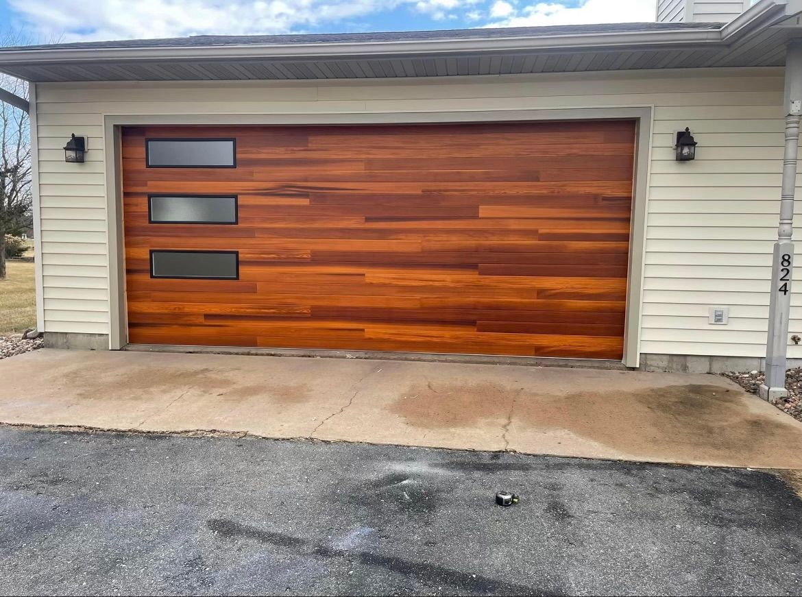 A wooden garage door is sitting in front of a white house.