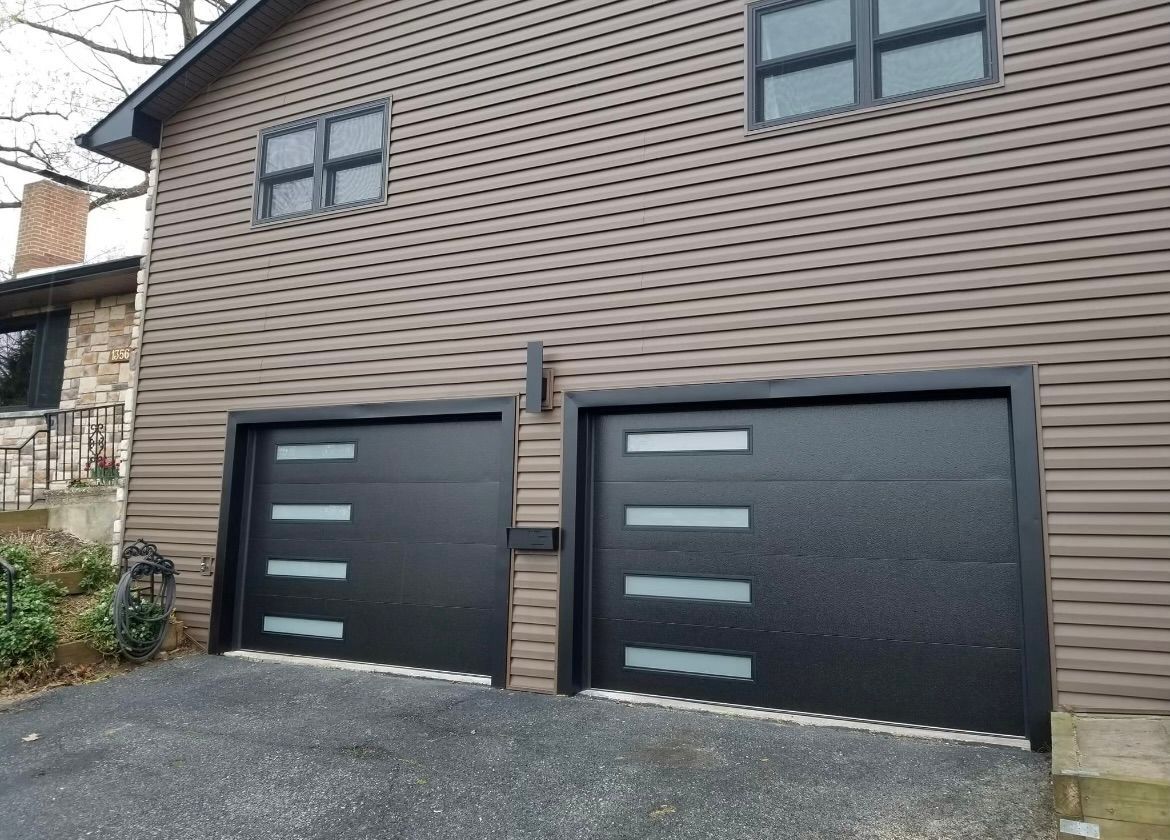 There are two garage doors on the side of a house.