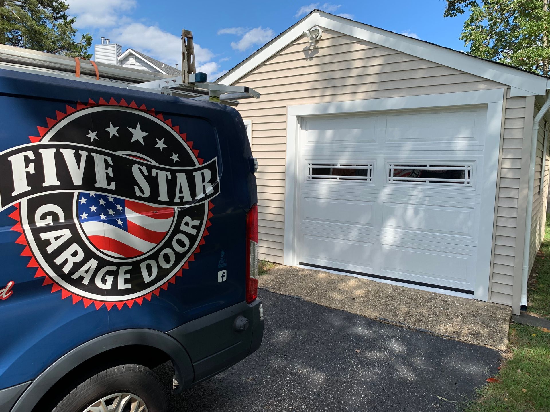 A blue five star garage door van is parked in front of a garage door.