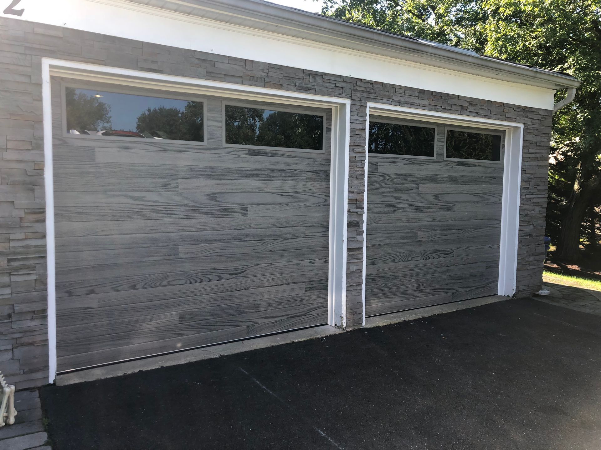 A garage with two garage doors and a driveway in front of it.