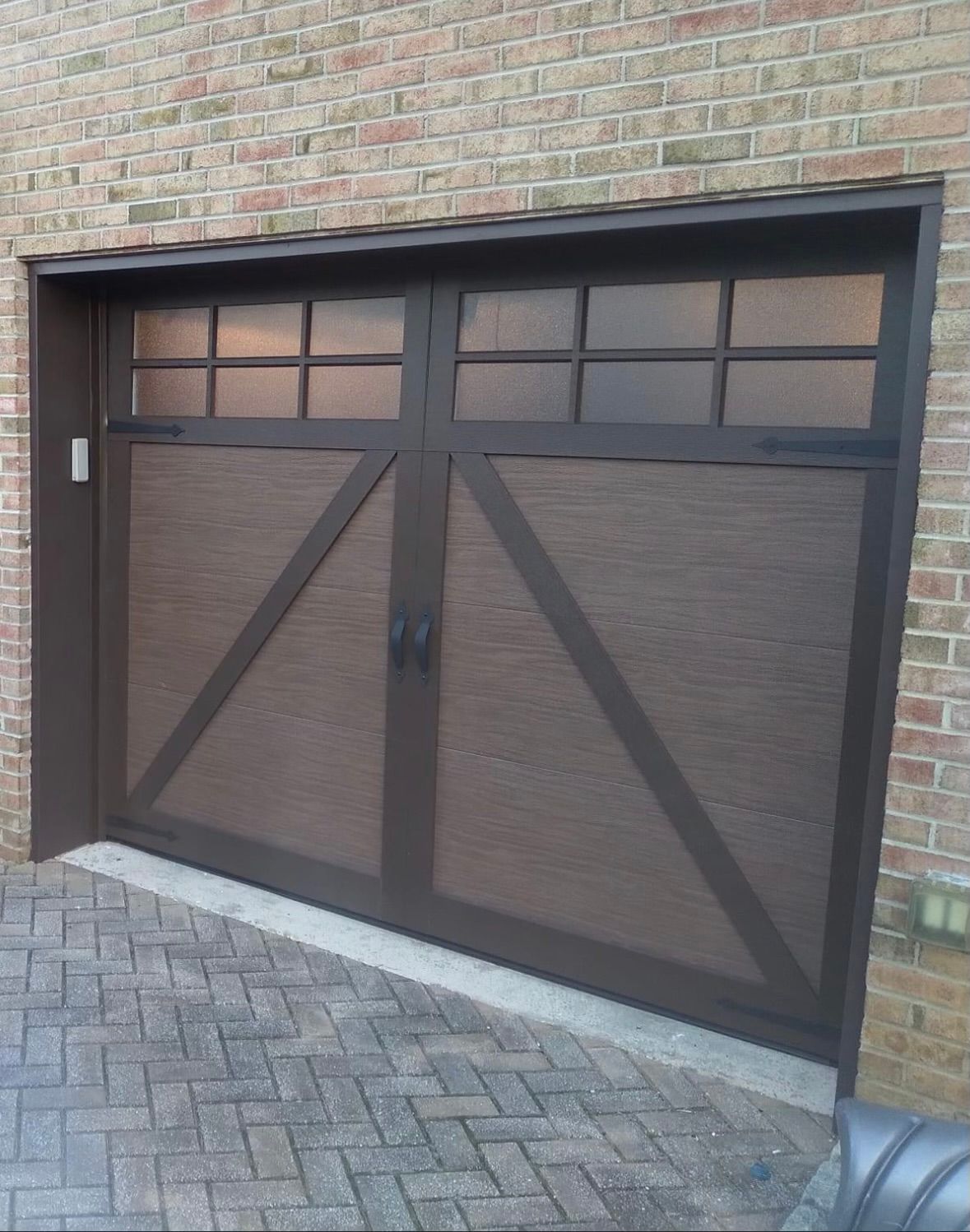 A brown garage door with a brick wall behind it