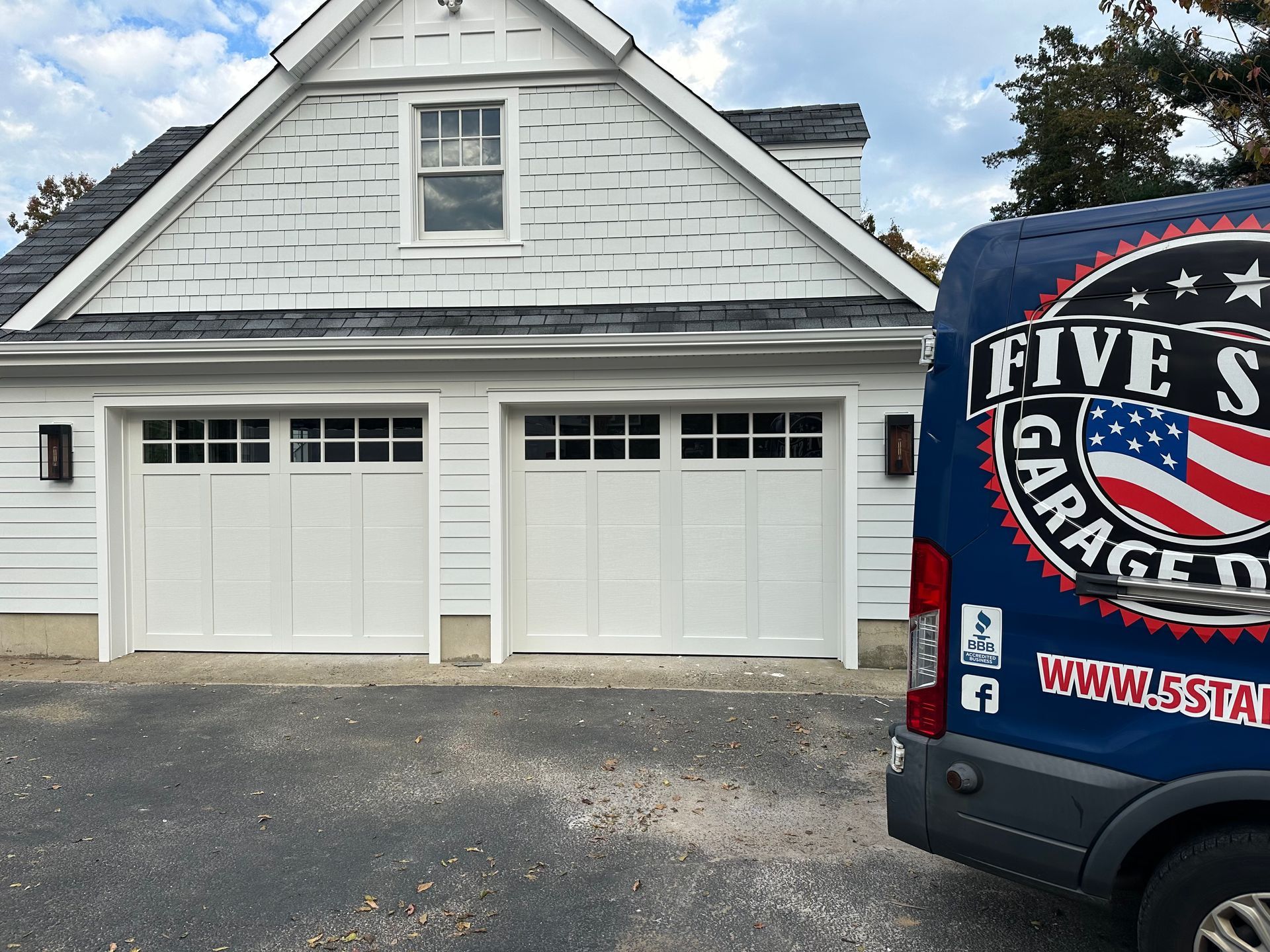 A blue van is parked in front of a white house.