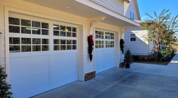 A white garage door with a christmas wreath on it.