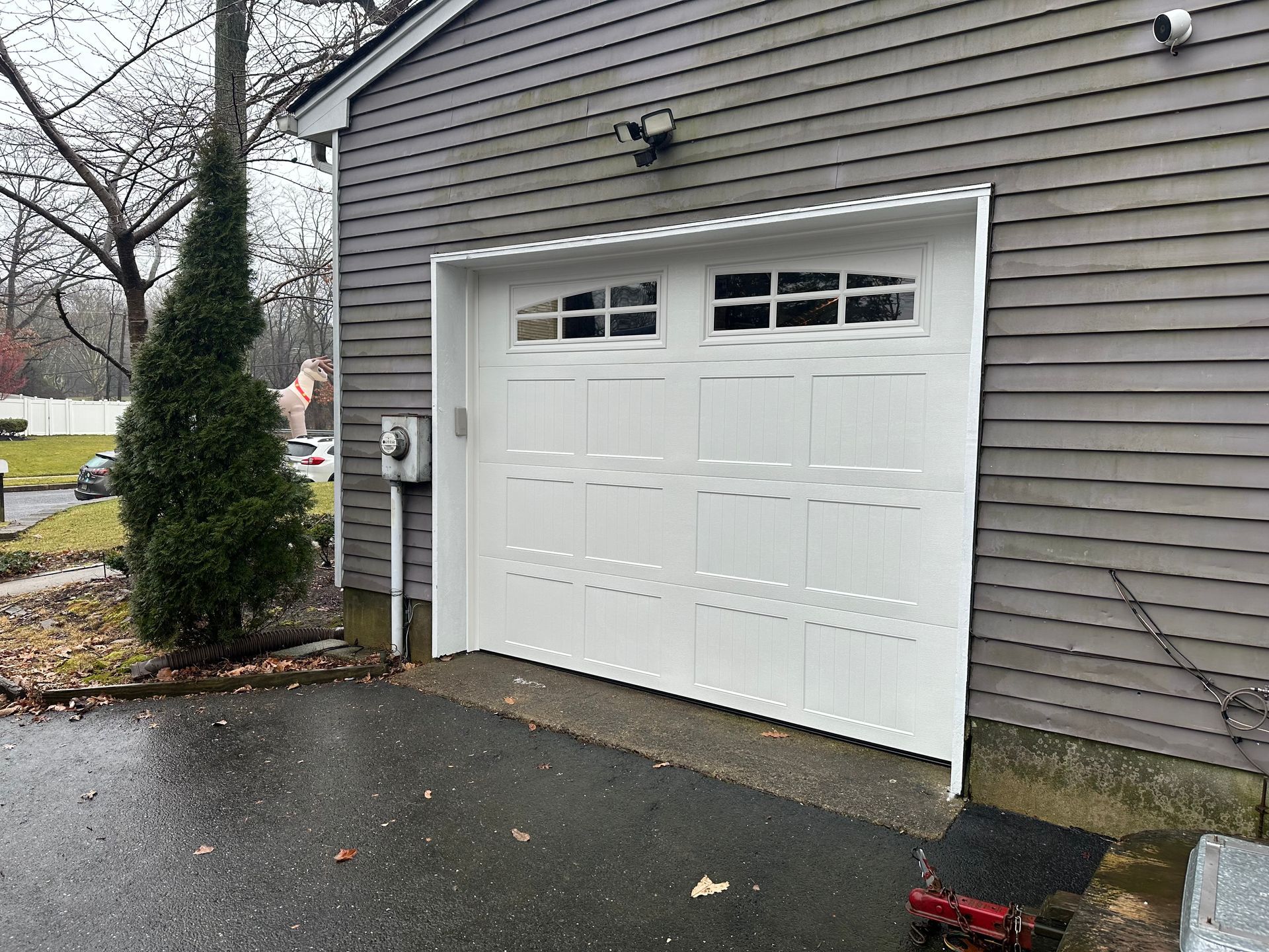 A white garage door is sitting on the side of a house.