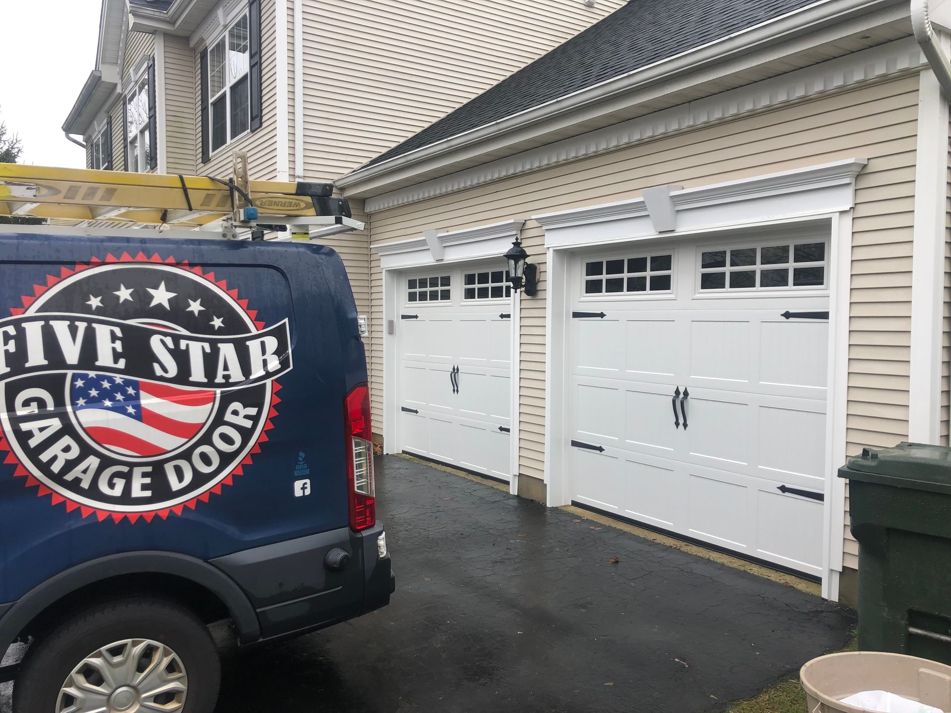 A five star garage door van is parked in front of a house.