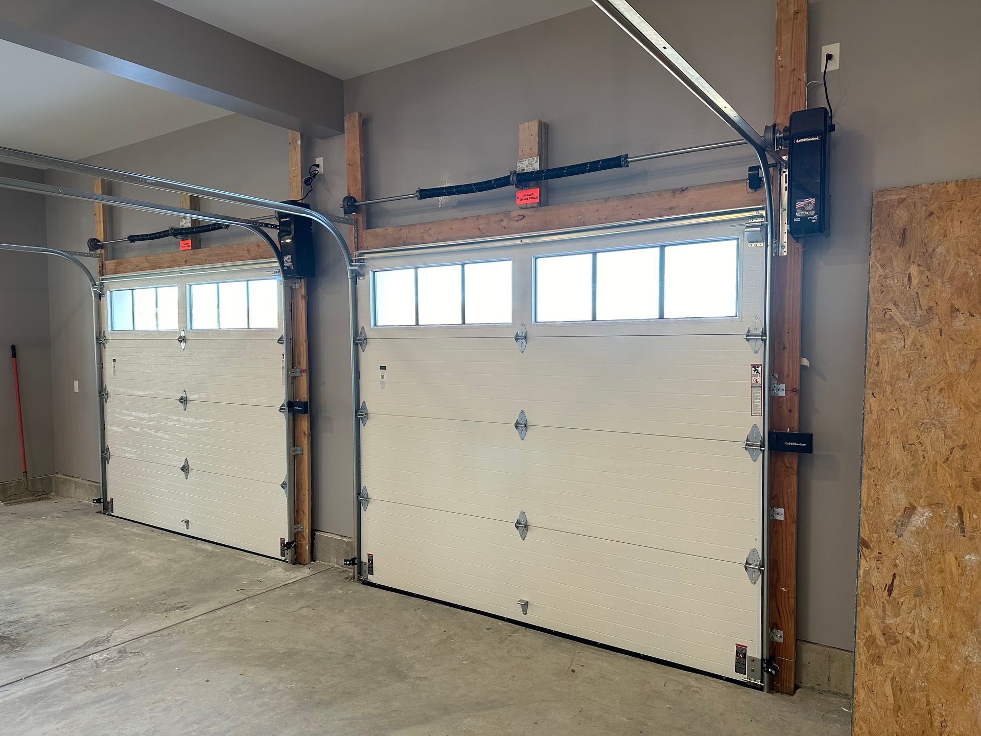 Two white garage doors are open in a garage.