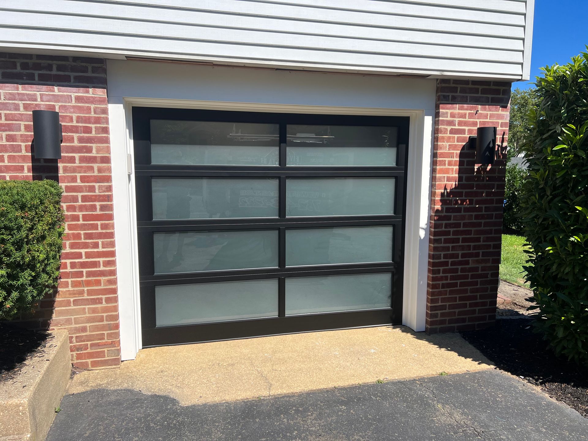 A black garage door is sitting in front of a brick house.