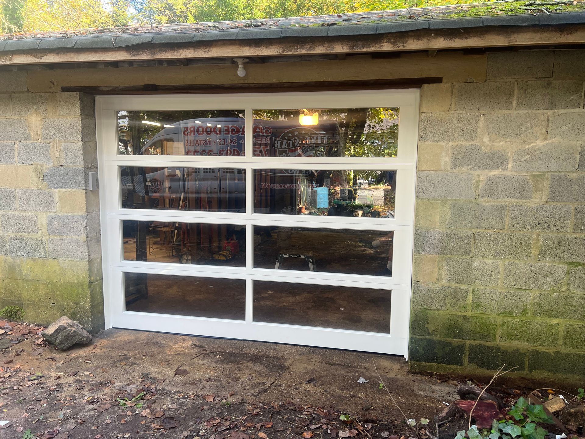 A white garage door with a lot of windows on a brick wall.