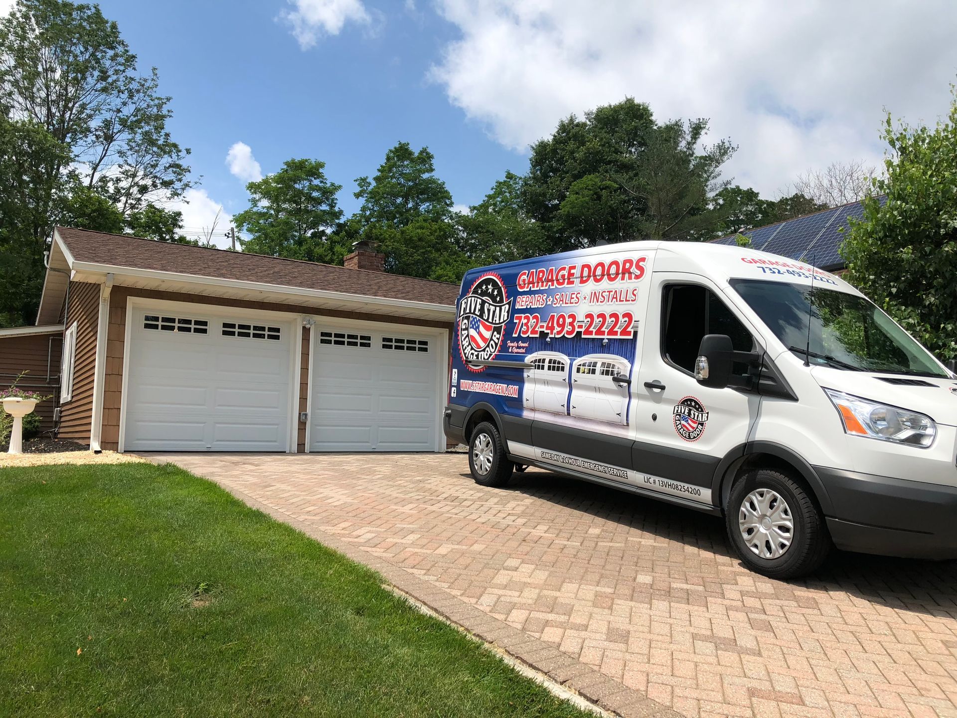 A white van is parked in front of a garage door.