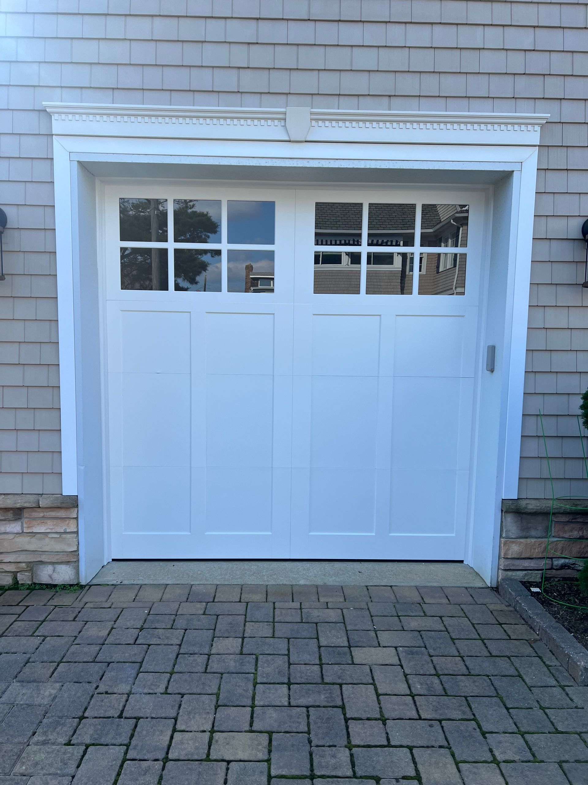 A white garage door is sitting on a brick driveway