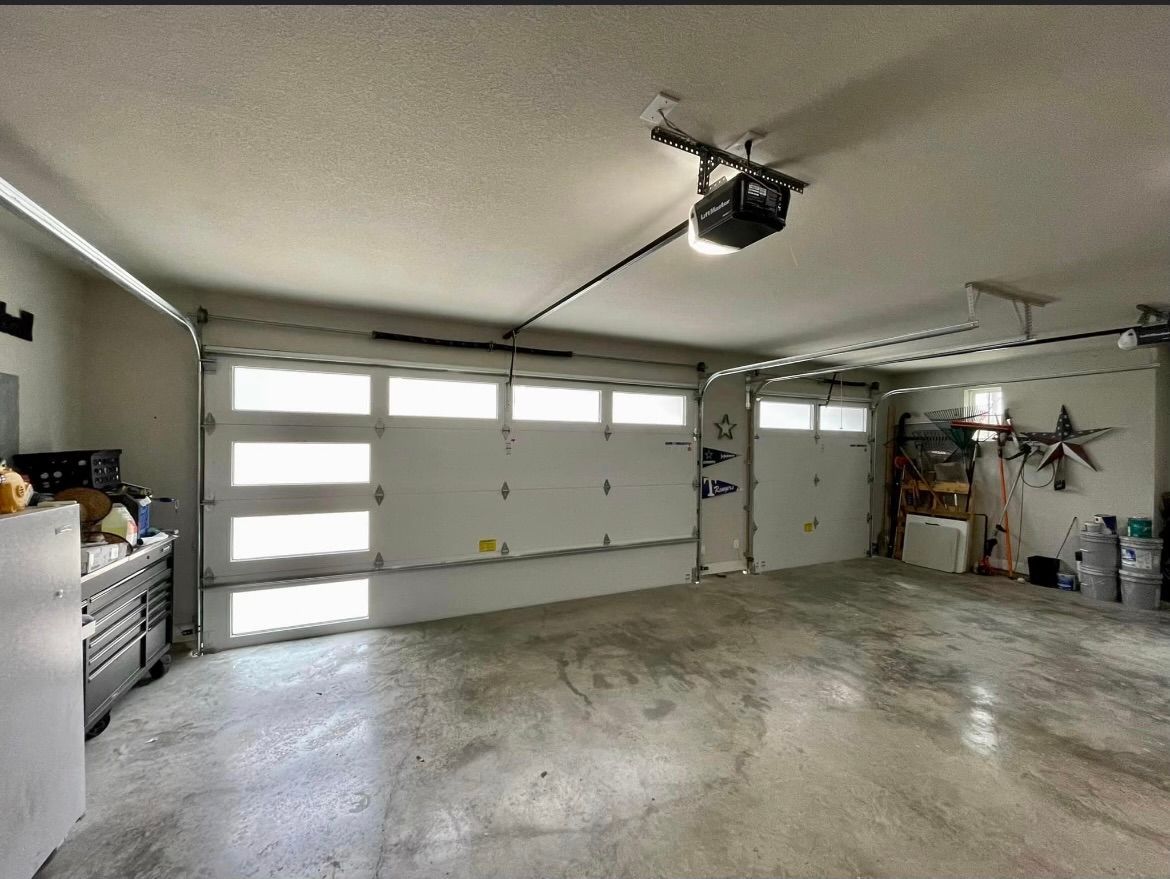 A garage with a garage door open and a ceiling fan.