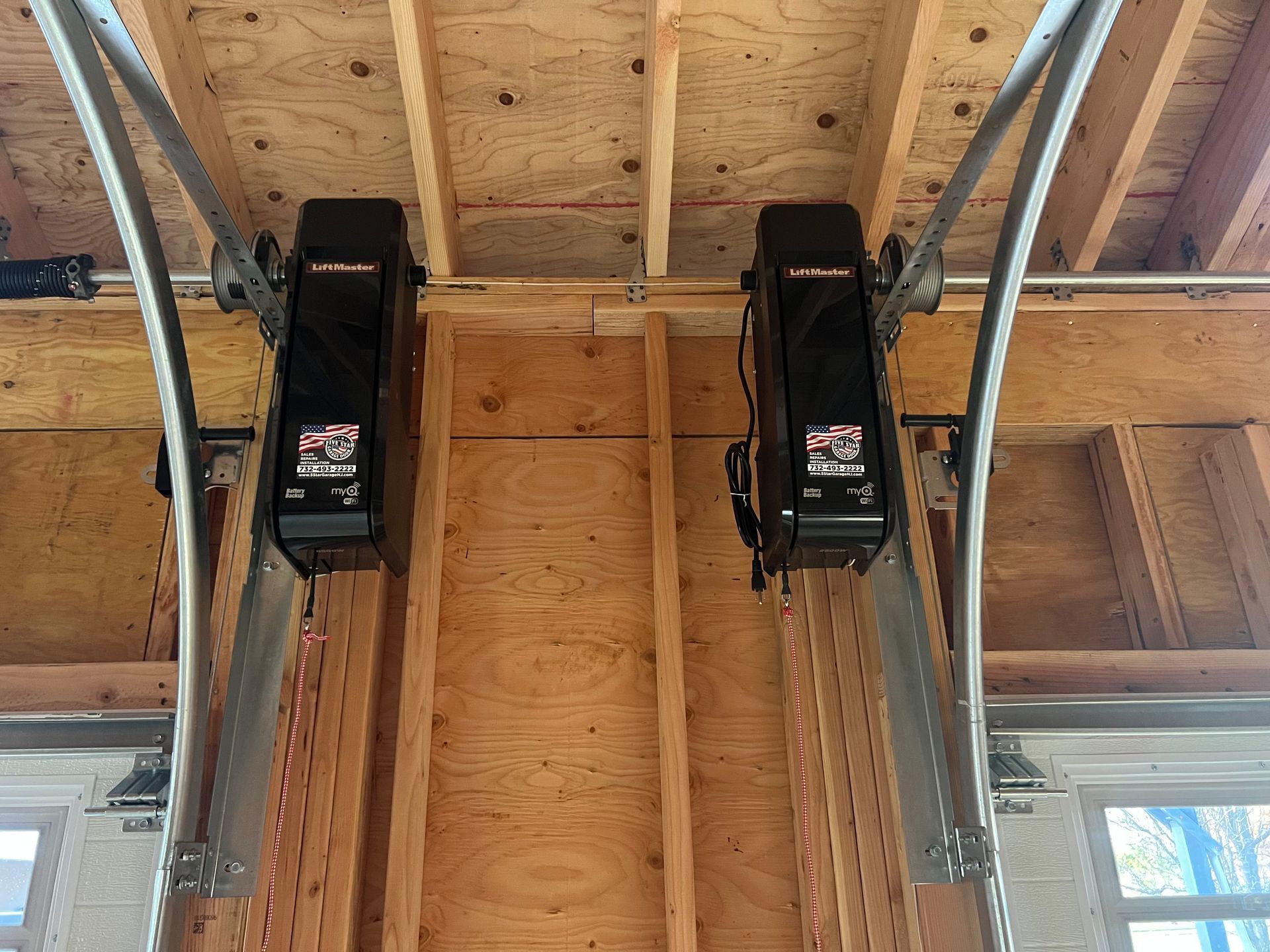 A garage door opener is hanging from the ceiling of a house under construction.