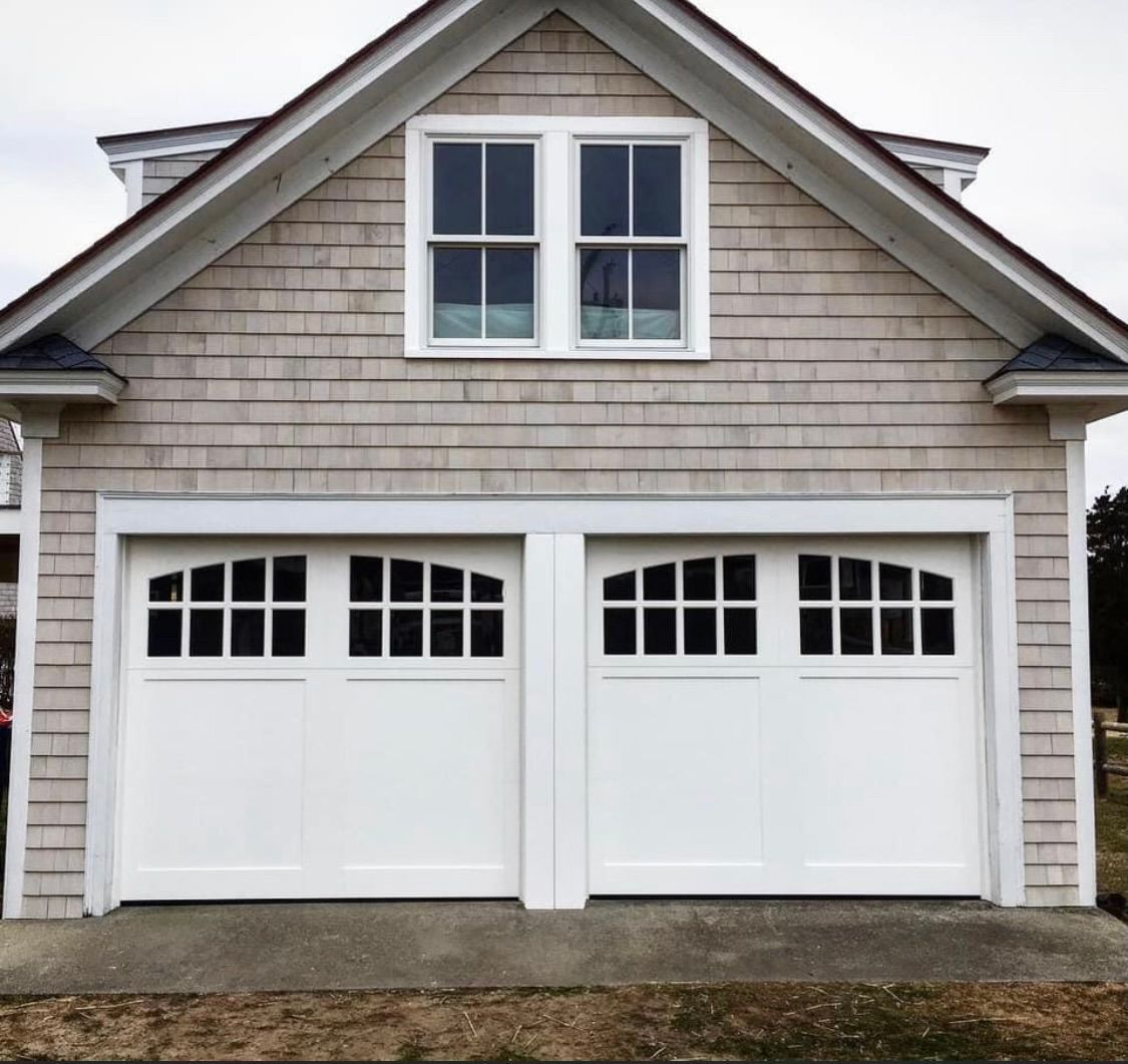 A house with two white garage doors and two windows