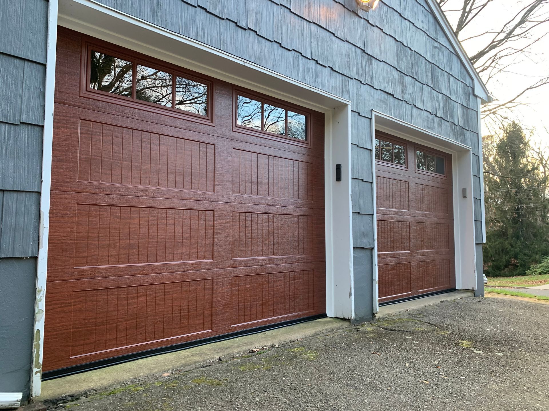 There are two garage doors on the side of a house.