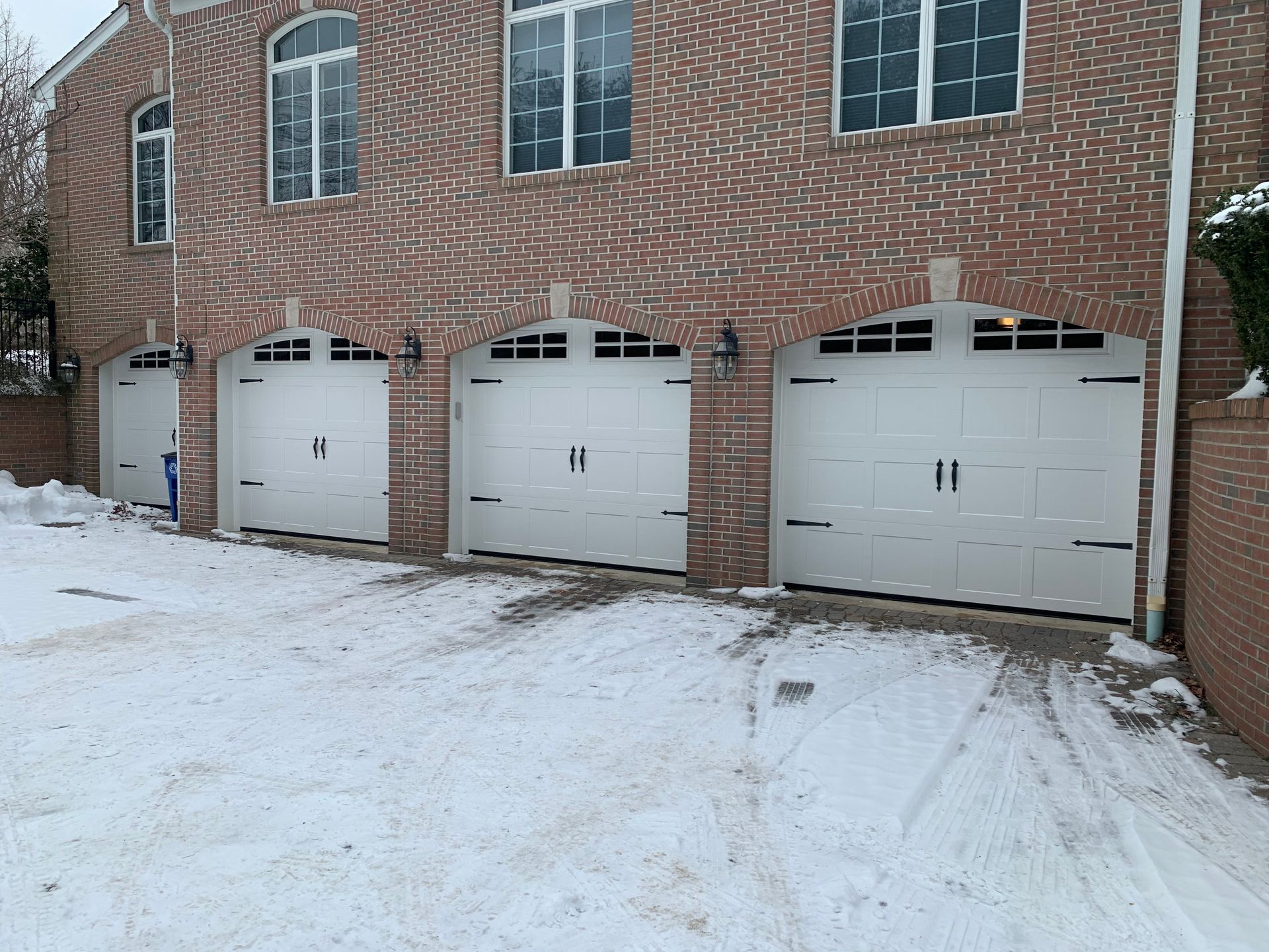 A row of white garage doors in front of a brick building