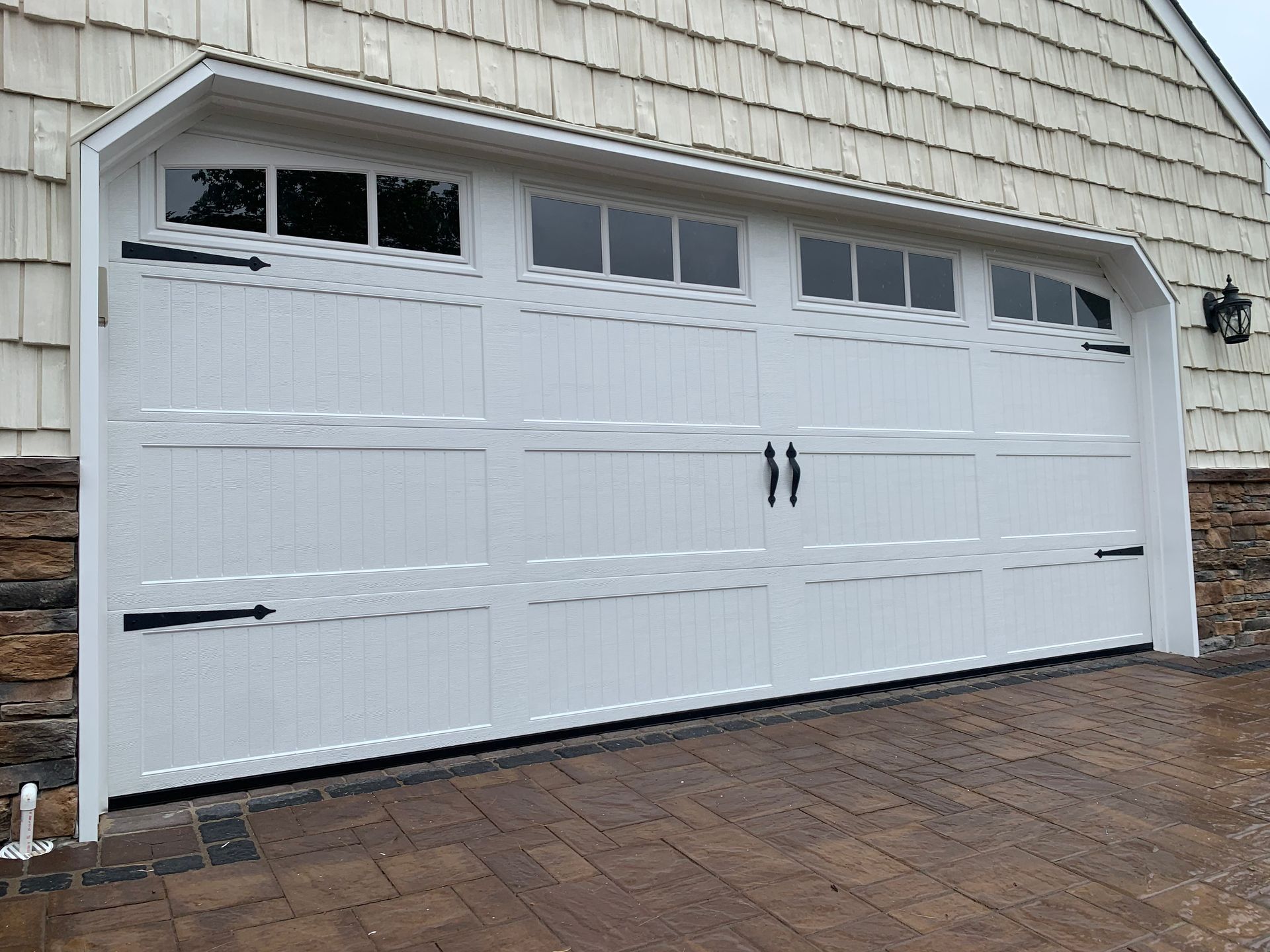 A white garage door is sitting in front of a house.