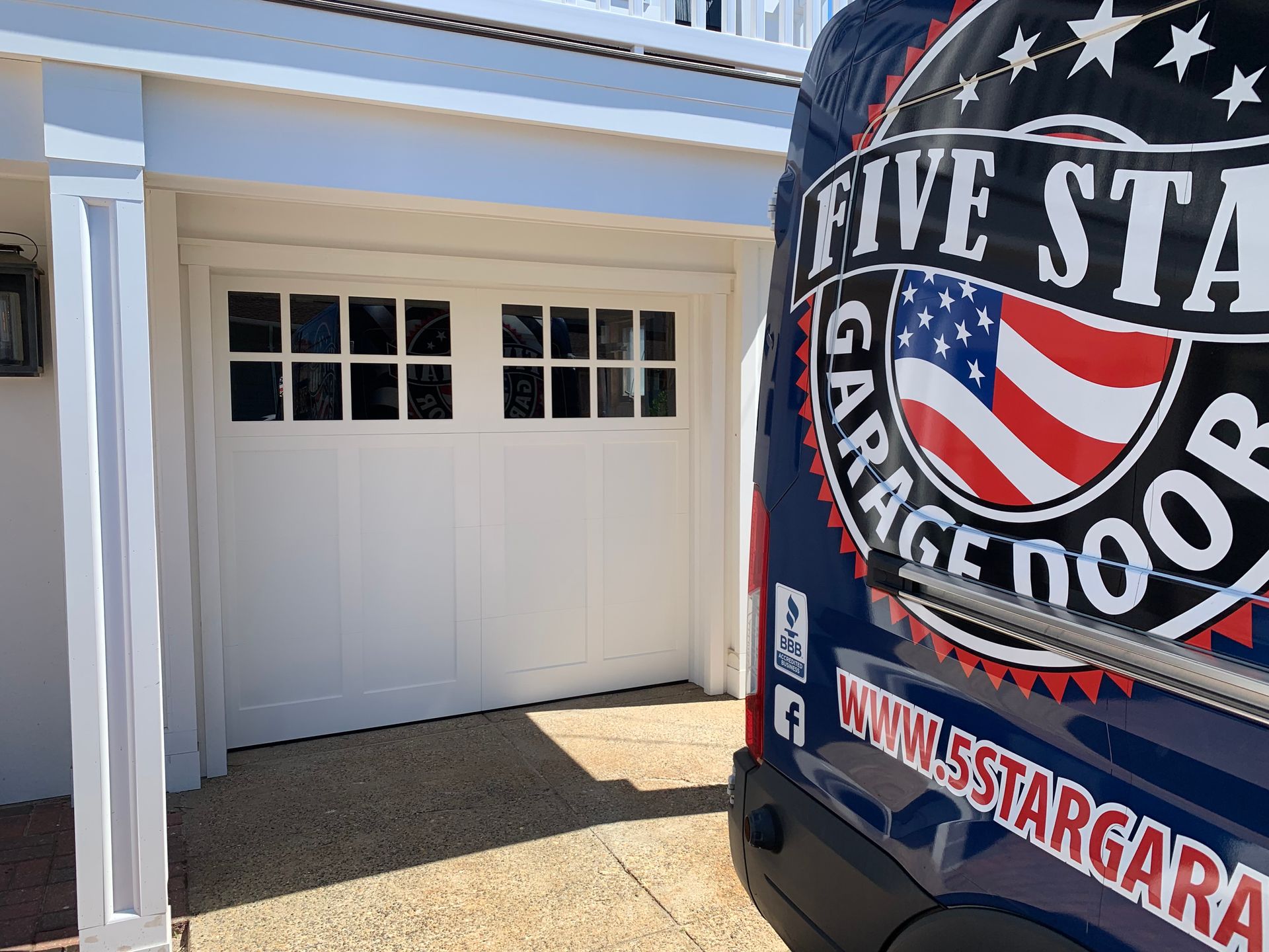 A blue five star garage door van is parked in front of a white garage door.