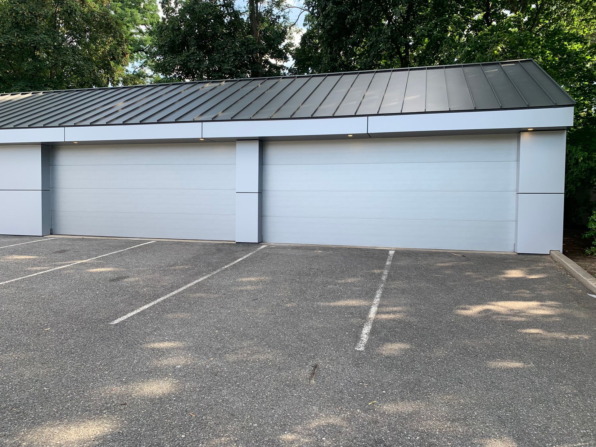 A white garage with a metal roof is in a parking lot.