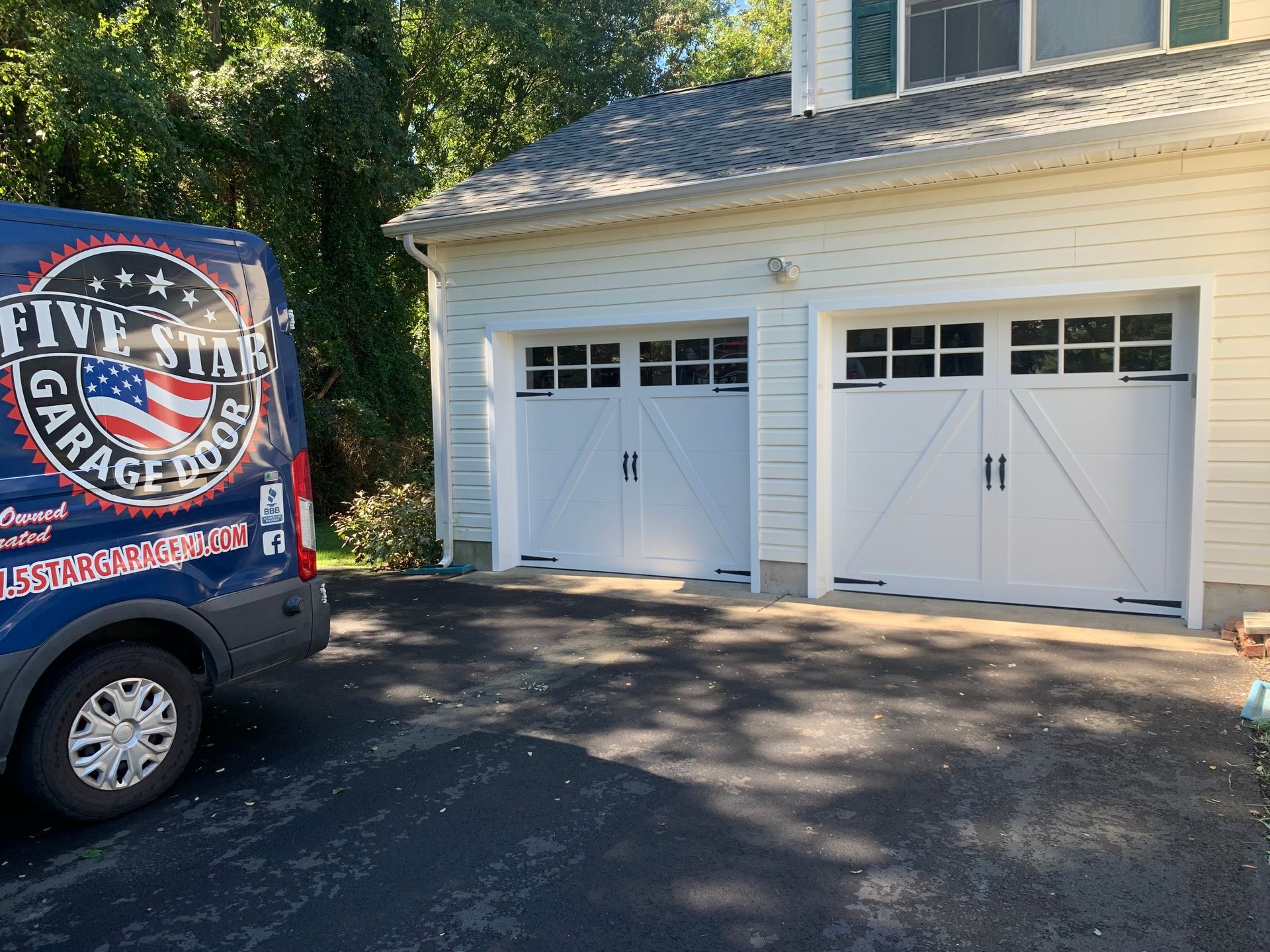 A blue van is parked in front of a white garage door.