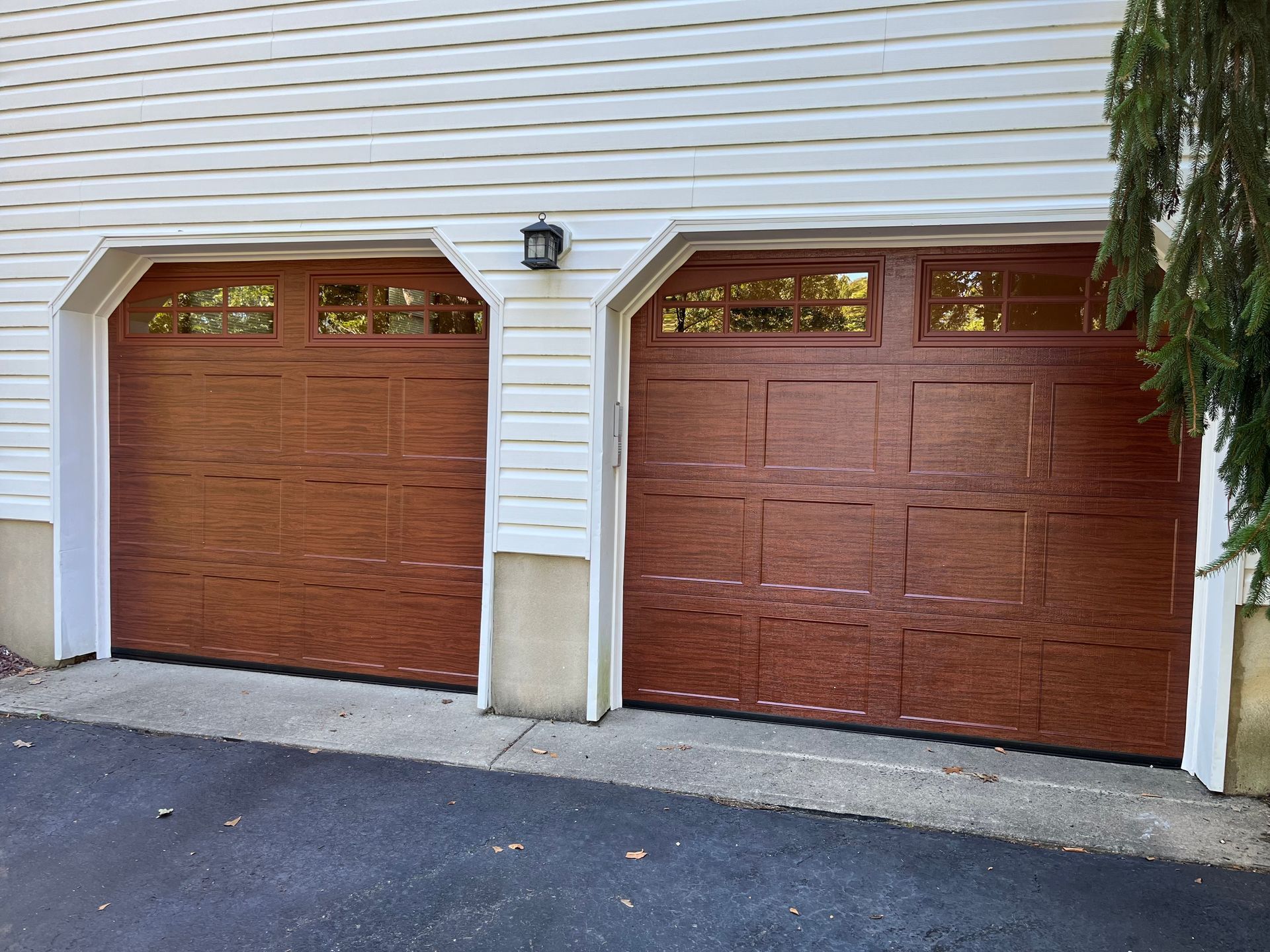 A pair of brown garage doors on a white house.