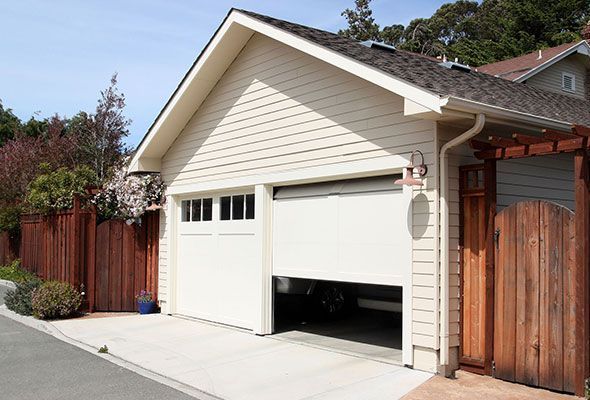 A white garage with a wooden fence in front of it.