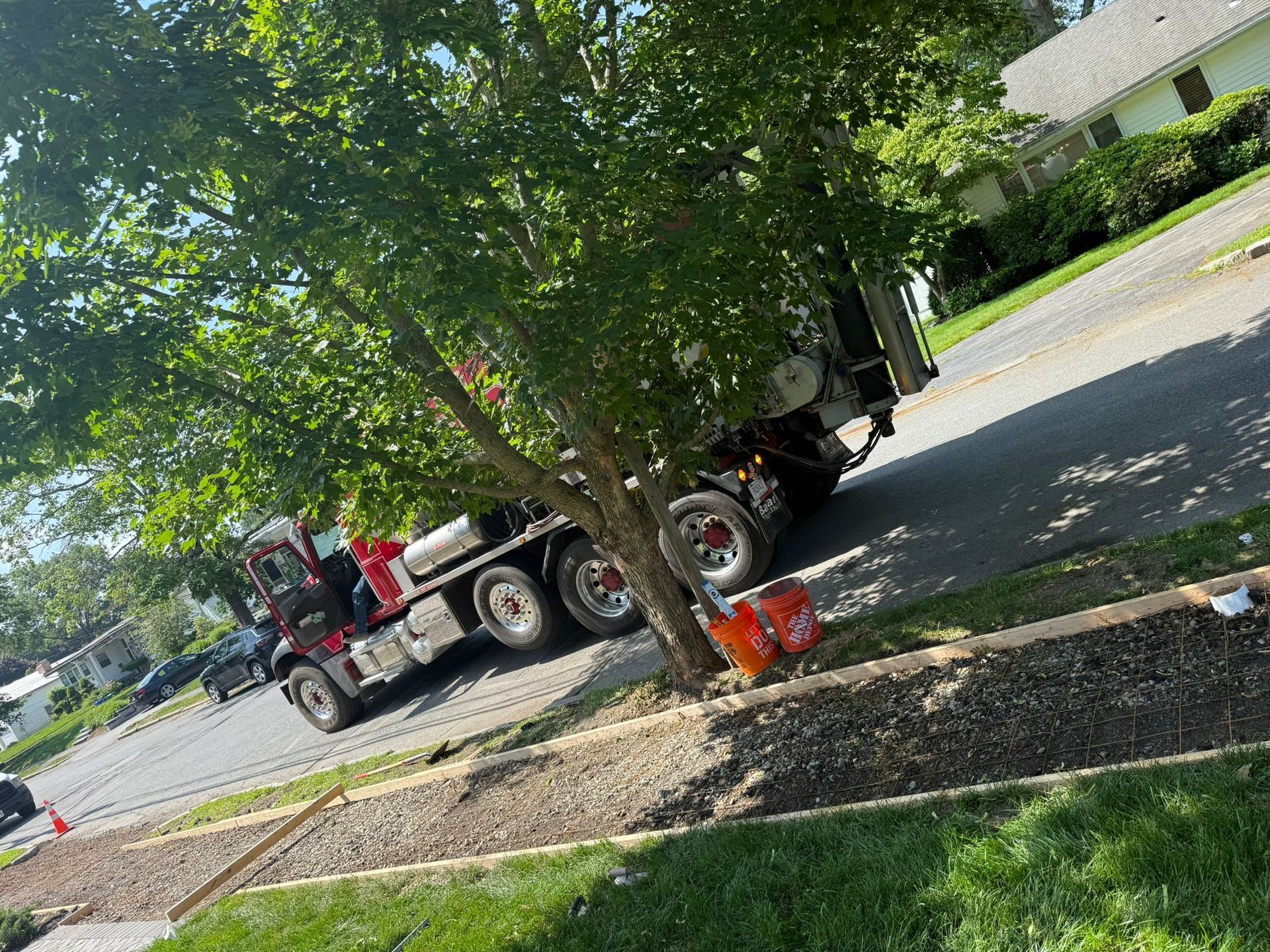 A cement truck parked next to a curb being worked on.