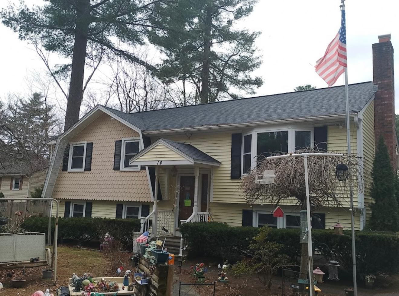 Yellow house with American flag, black shutters, and front porch.