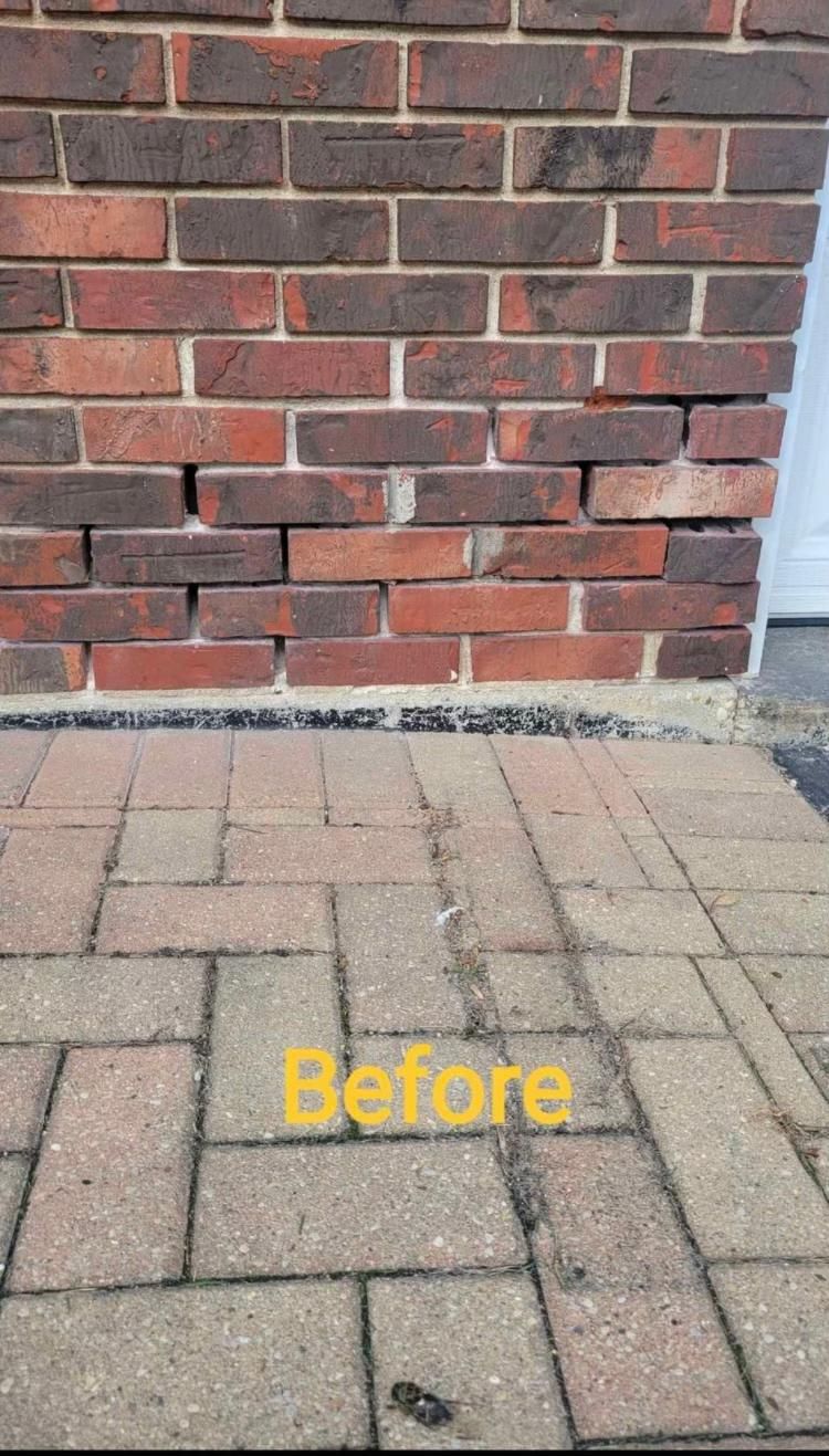 Brick wall with horizontal cracks near the base. Paving stones in foreground, 