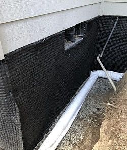 Black dimpled foundation wrap with drain pipes and window well