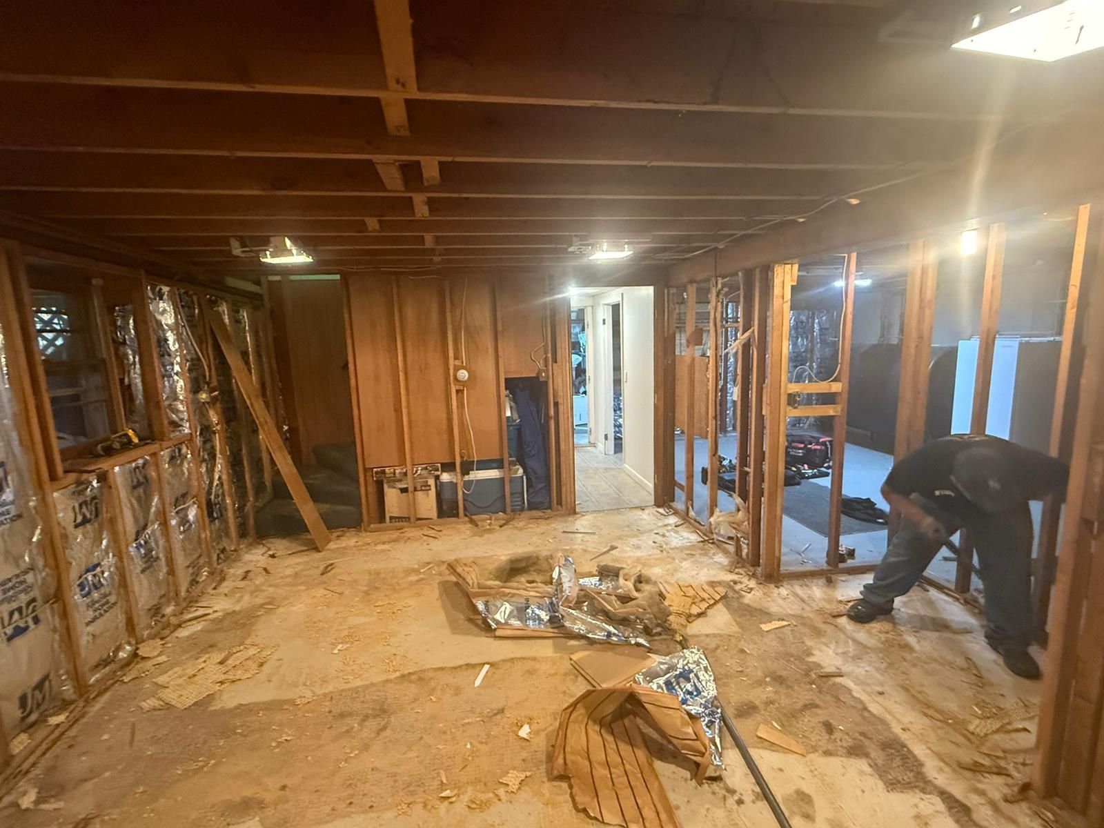 Interior room under renovation, exposed framing, insulation, debris on floor