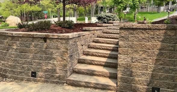 Stone staircase built into a retaining wall in a landscaped garden.