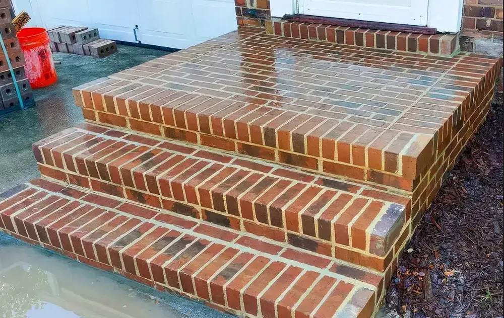 Brick steps and landing wet from rain, leading to a white door.