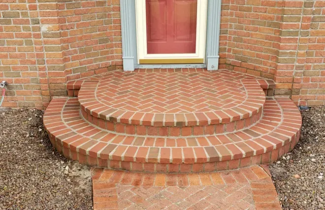 Brick steps leading to a front door with a red door 