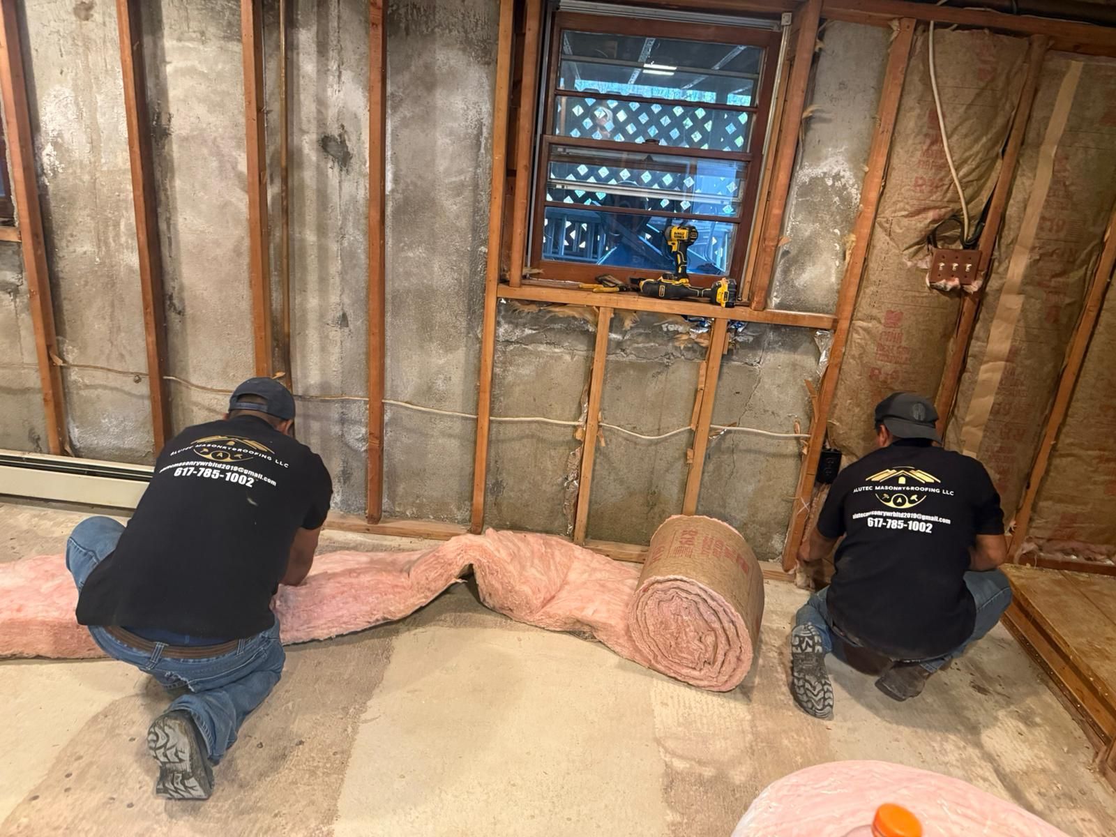 Two men installing pink insulation