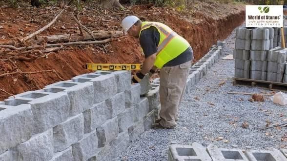 Construction worker building a retaining wall with concrete blocks