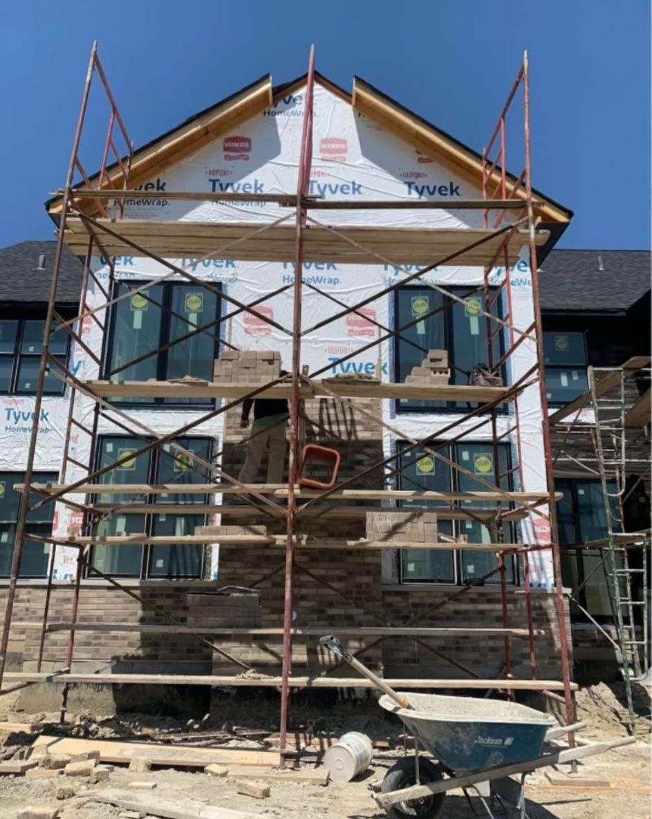 Building under construction with scaffolding and stone siding.