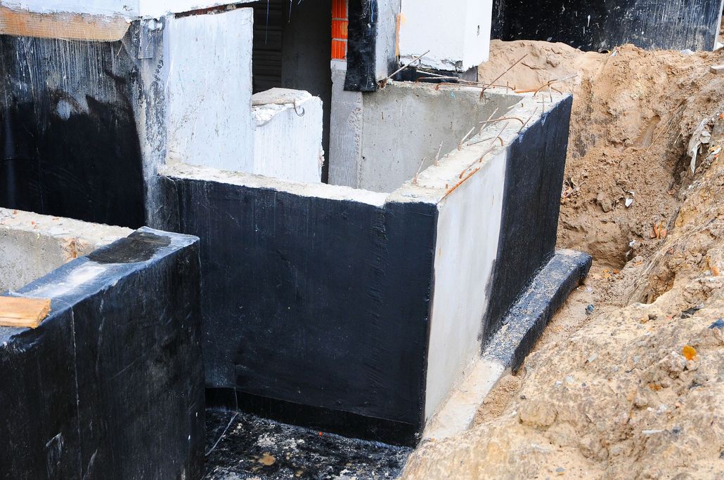Foundation walls under construction, coated with black sealant