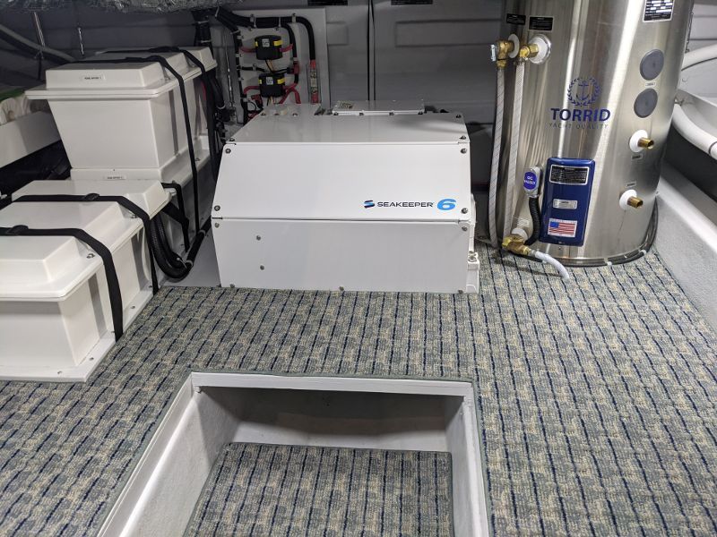 A stainless steel water heater is sitting on the floor of a boat.