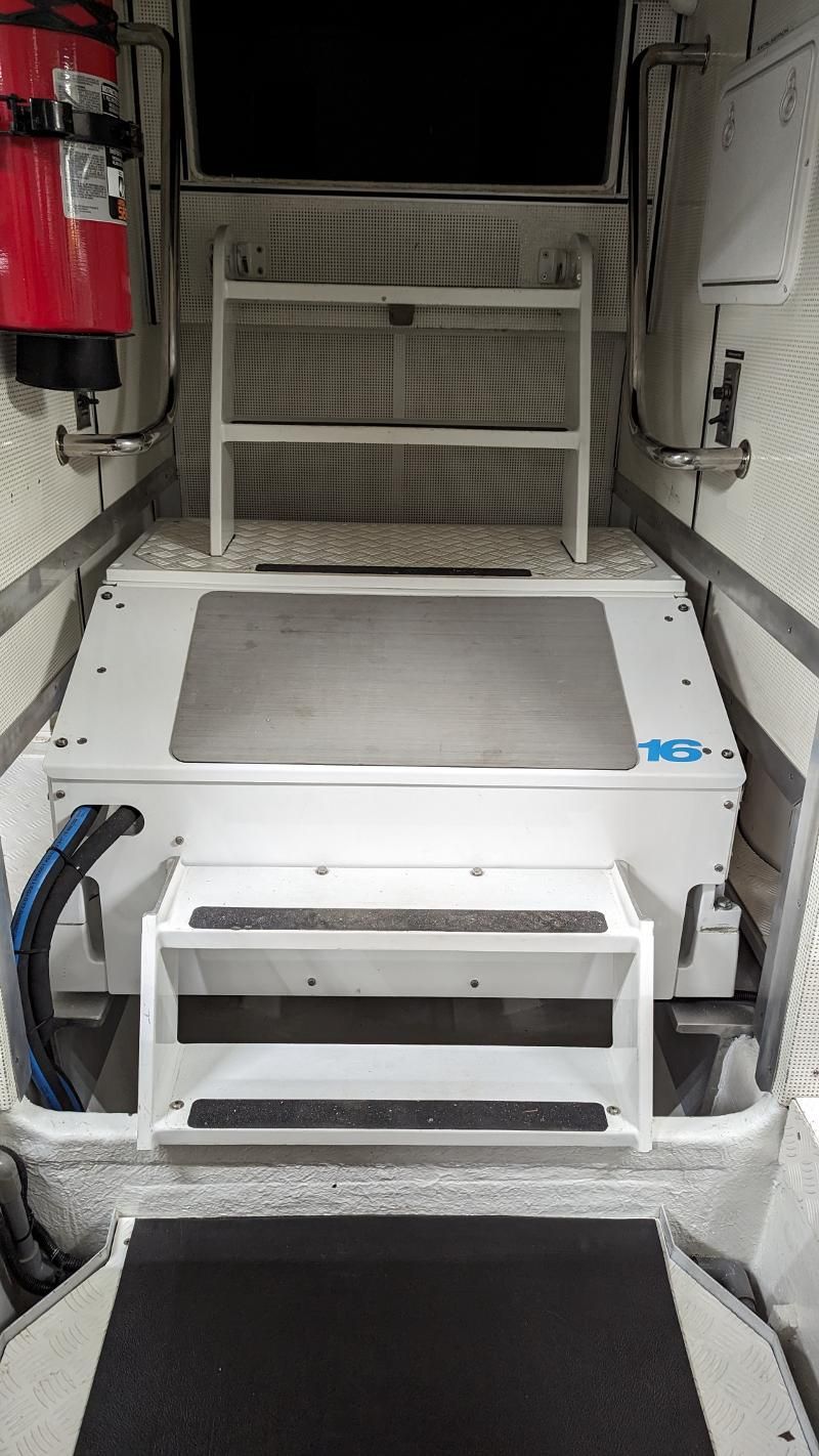 The inside of a boat with stairs and a fire extinguisher.